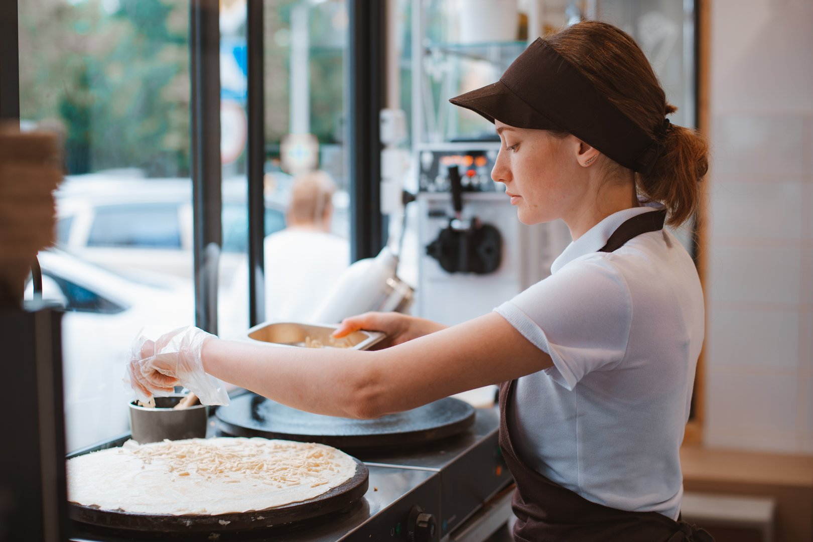 Portrait woman chef baking pancakes in an apron uniform. Fast food service of the city. fast food restaurant is a small business.