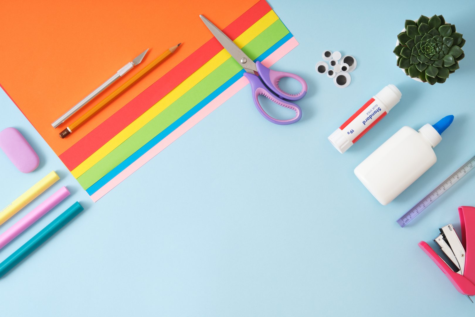 Frame made of paper cutting tools, scissors, cutter, cutting mat and colored paper. DIY, handicraft concept. Flat lay, copyspace