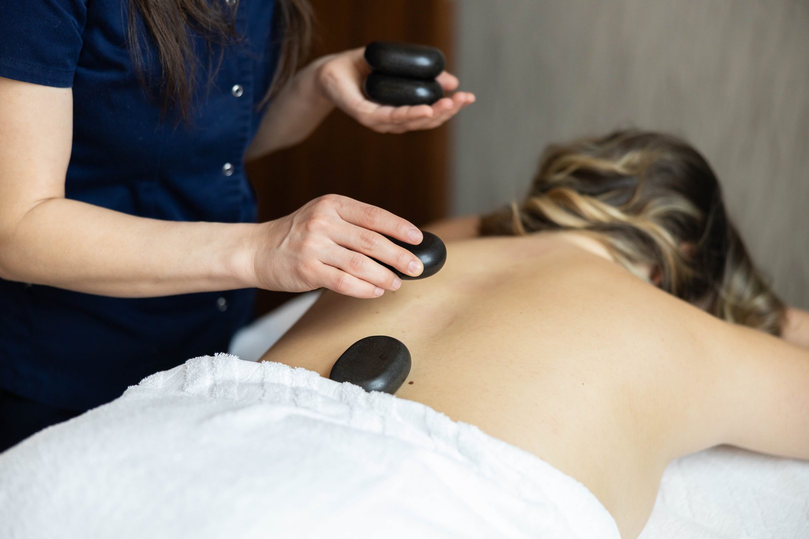 The therapist is carefully placing hot stones on a client's back for a soothing and therapeutic massage experience.