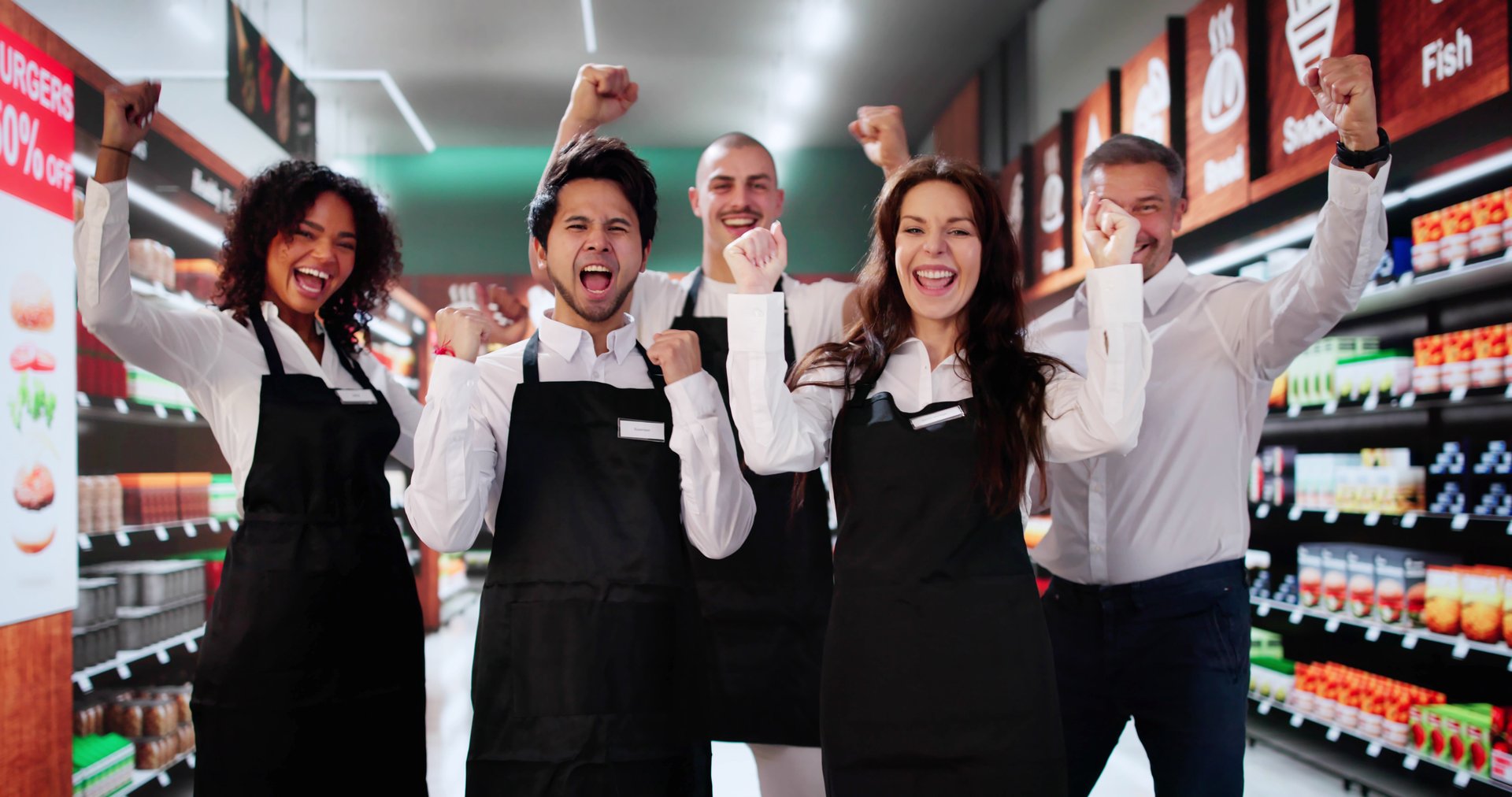 Happy Supermarket Employees In Shop. Group Success Celebration