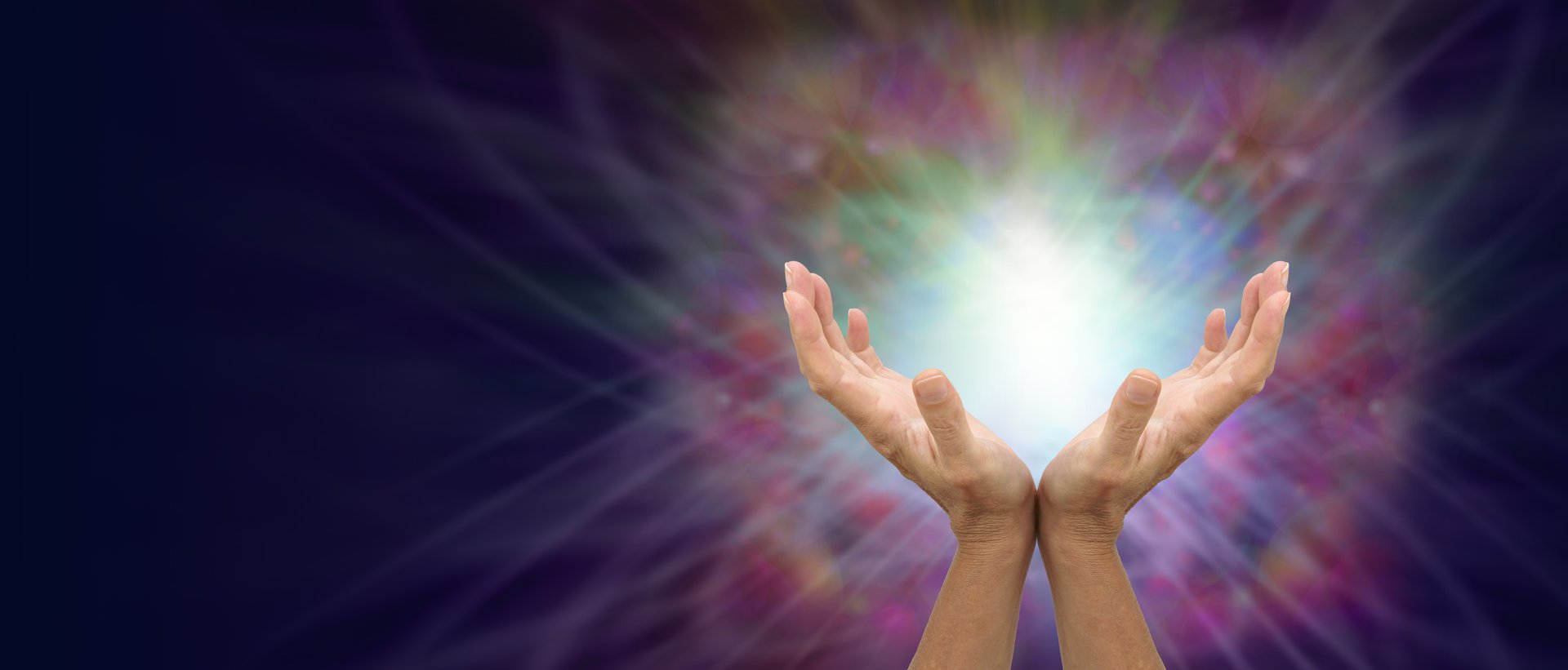 female hands facing upwards against a beautiful colourful energy formation with a space for copy on the left side