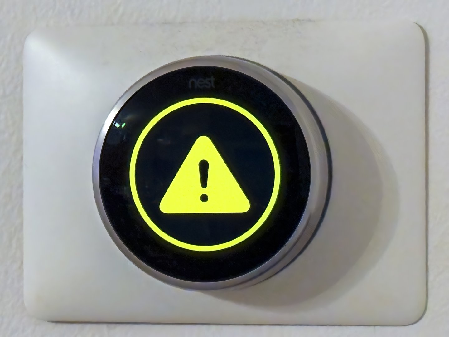 Calgary, Alberta, Canada. Jan 19, 2026. A Google Nest smart thermostat displaying a yellow triangle exclamation point warning symbol.