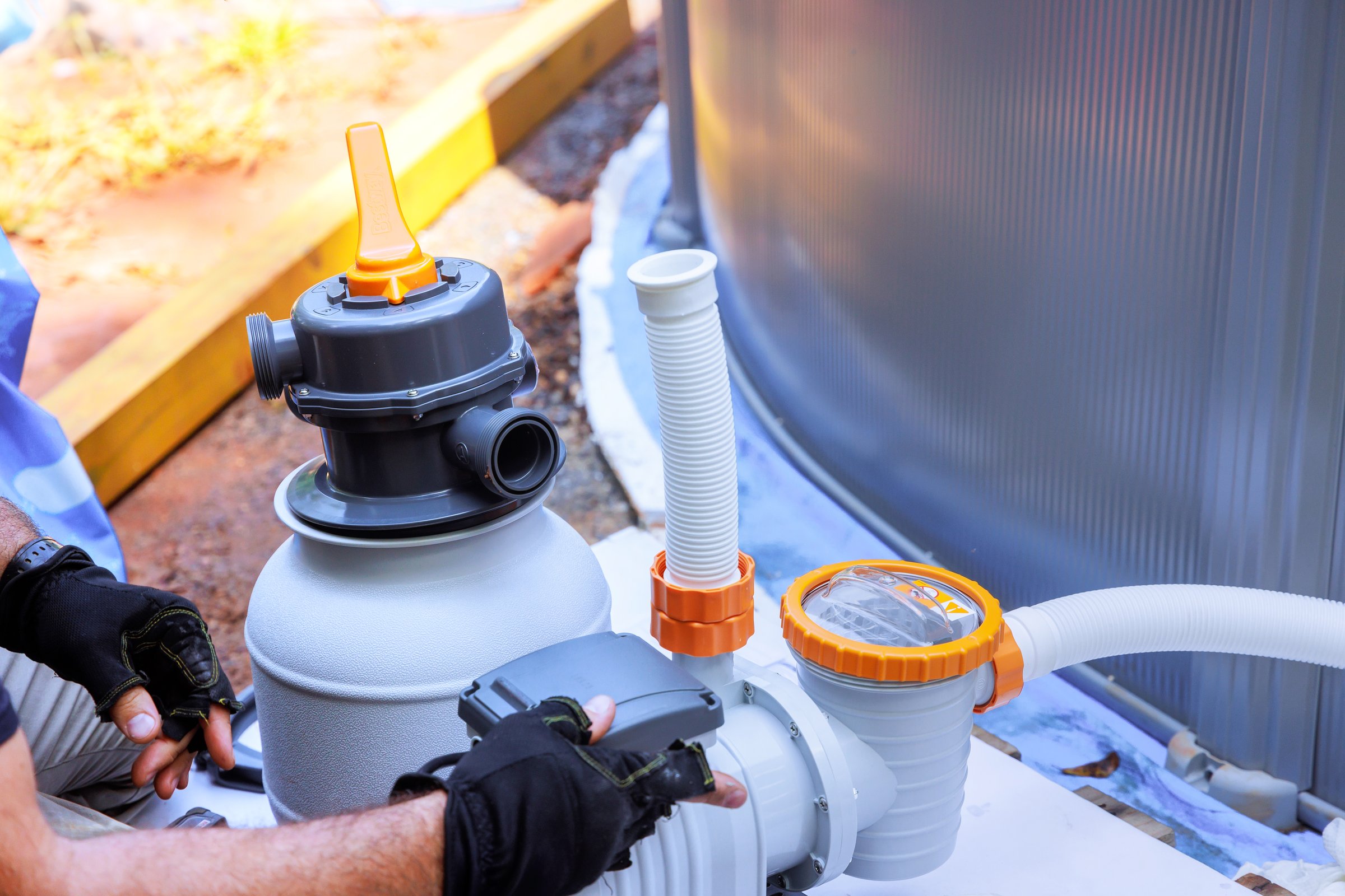 Maintenance workers assemble sand filter system tank, as well as equipment for cleaning swimming pools