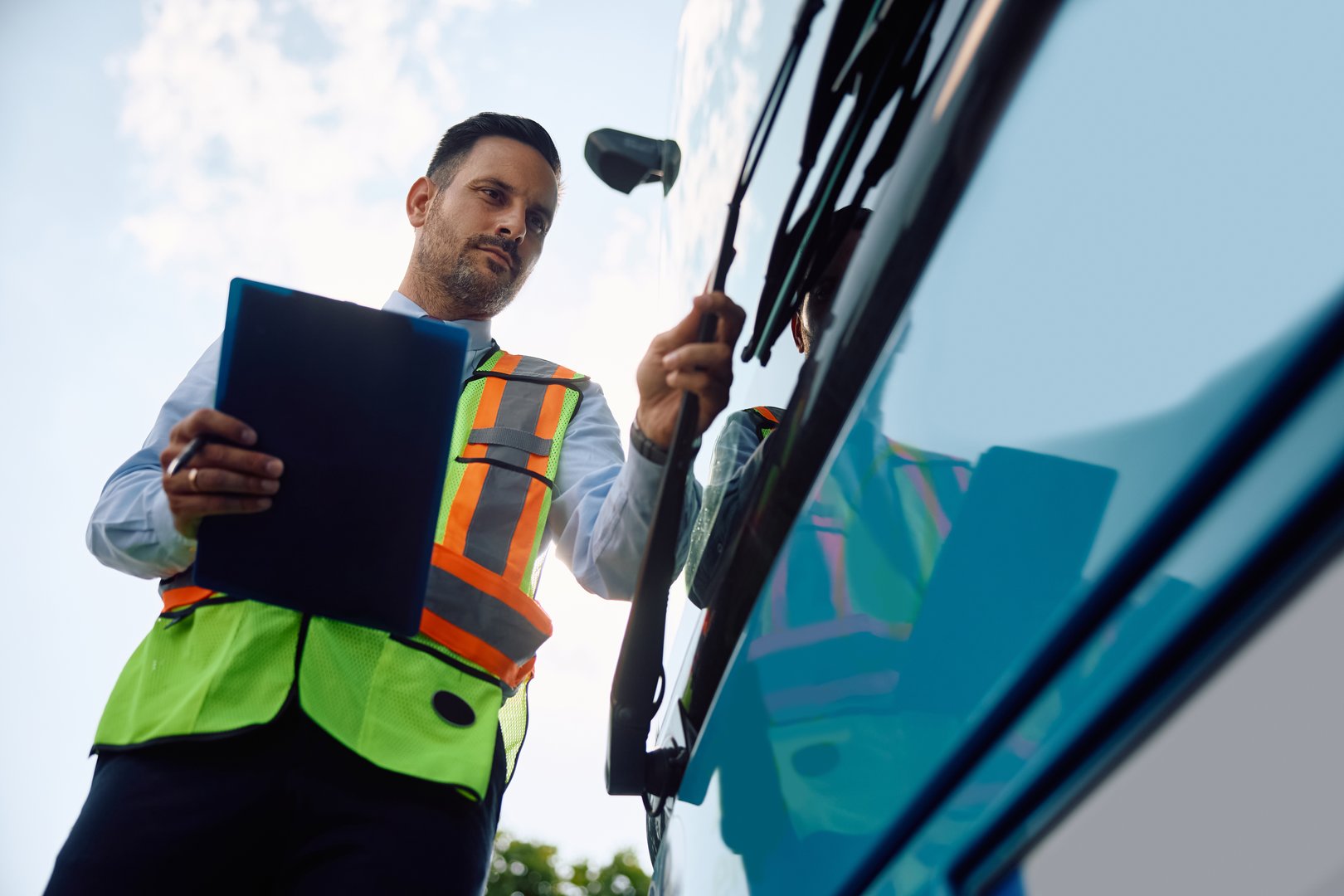 Low angle view of driver examining bus while preparing for the ride. Copy space.