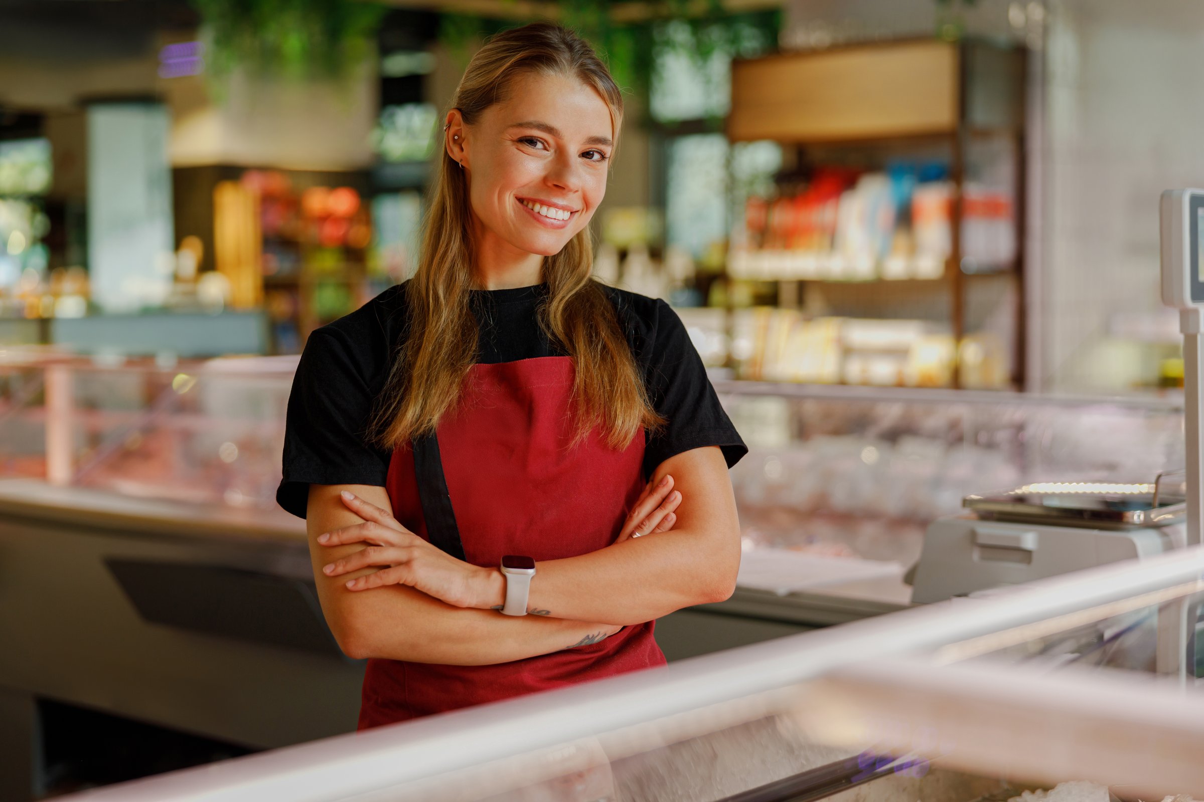 In a vibrant restaurant filled with color, a cheerful young woman confidently poses in her apron, embodying joy