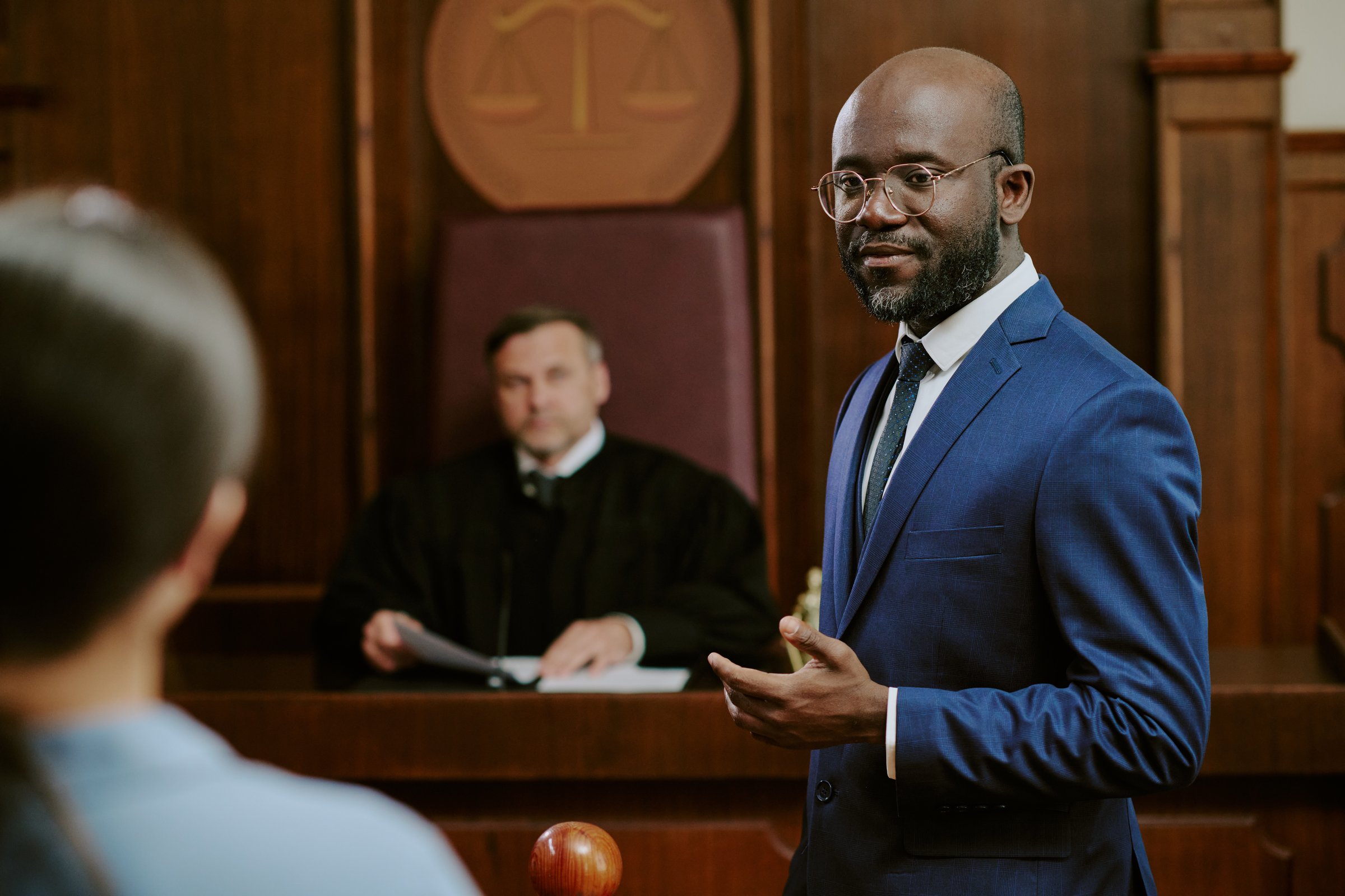 Black middle aged man standing and gesturing while addressing courtroom