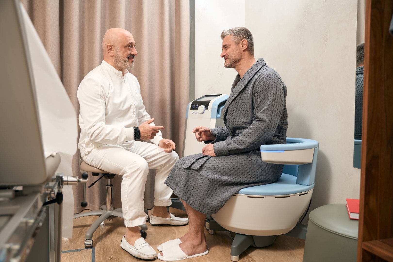 Full length side view portrait of handsome Caucasian males in talking while sitting in the modern medicine office