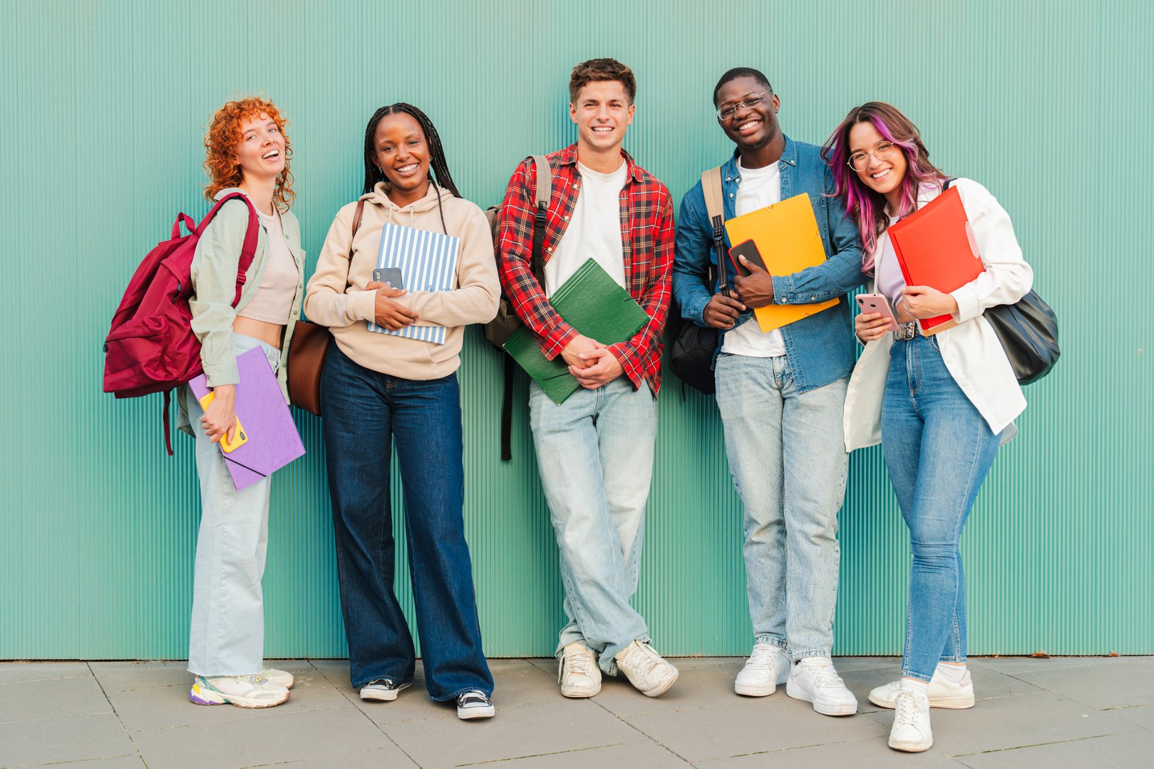 Enthusiastic group of friendly students standing together with notebooks and folders, exuding joy as they celebrate their academic journey and the bonds of friendship formed during their studies. High quality photo