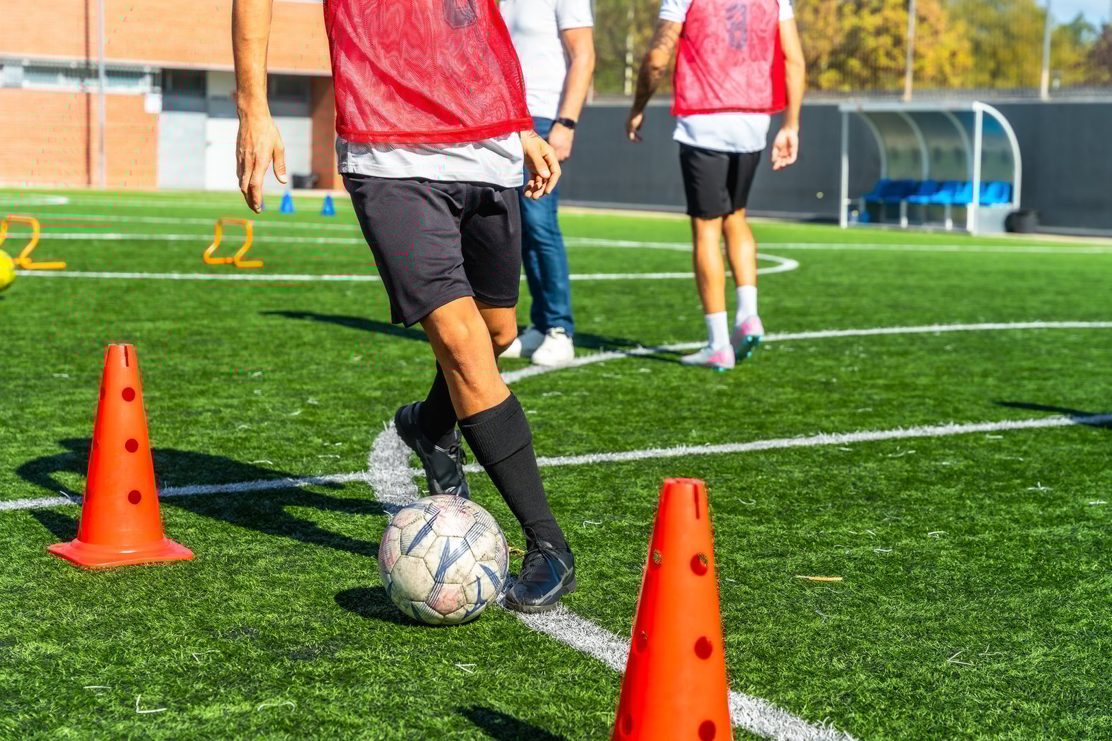 Jugador driblando entre conos naranjas - entrenamiento de agilidad