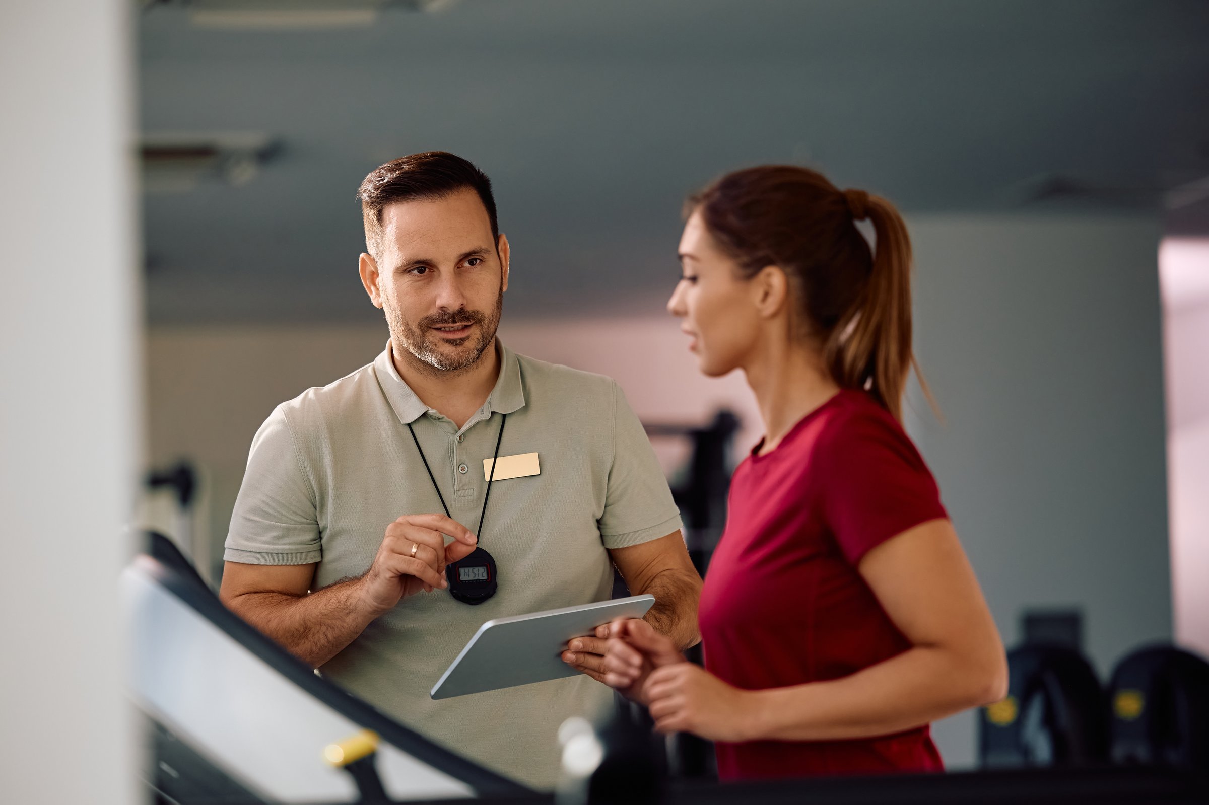 Fitness instructor talking to a sportswoman during exercise class at health club.