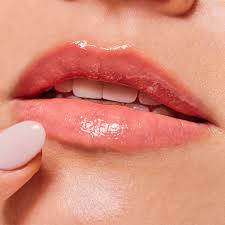 Close-up of glossy pink lips with a finger touching them, highlighting lip texture and shine.