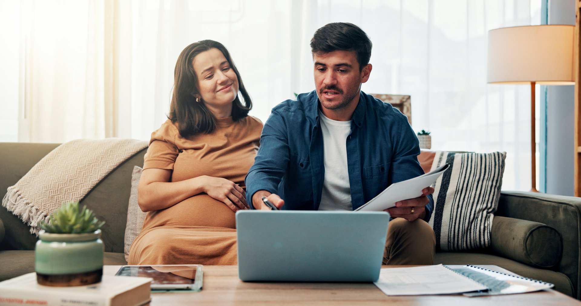 Pregnant woman, man and happy with finance in home on sofa with documents, planning and laptop in lounge. Couple, parents and smile with review, savings and discussion with budget, payment or bills