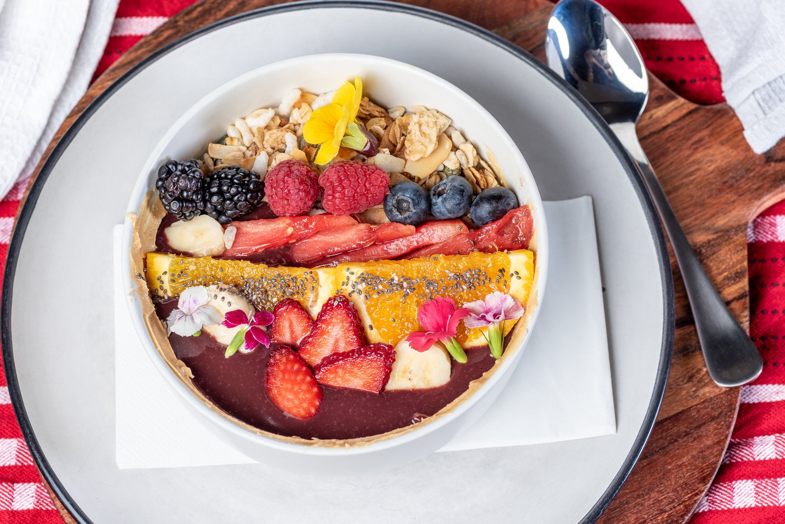 An Acai bowl topped with granola, banana, watermelon, oranges, berries