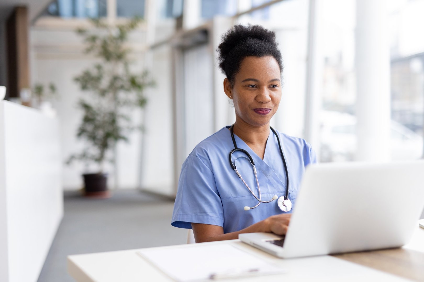 Skilled African American nurse reviewing patient data on a laptop