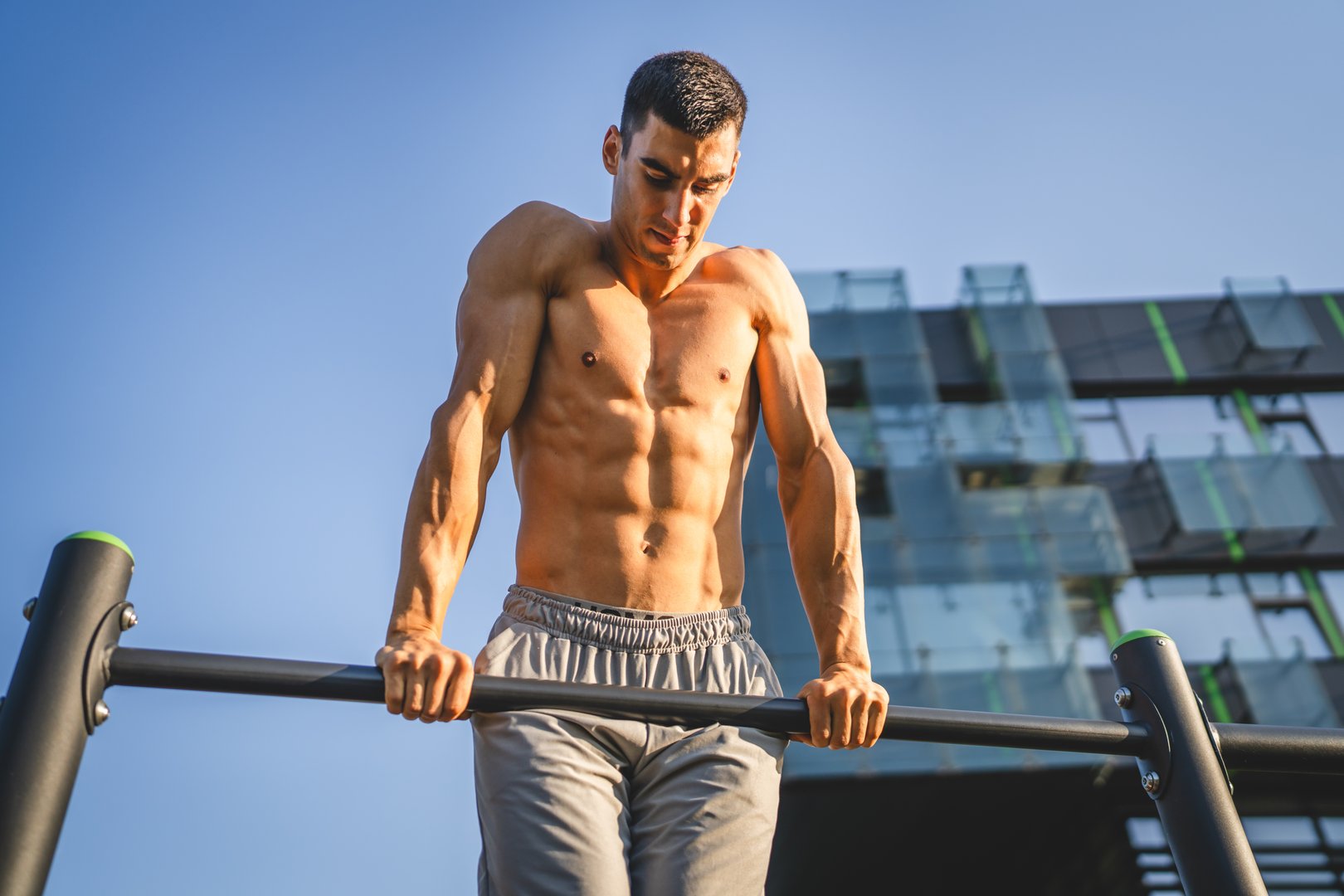 One man young adult caucasian male athlete training at outdoor open gym pull ups exercise healthy lifestyle and recreation training concept in the city in summer day real people copy space