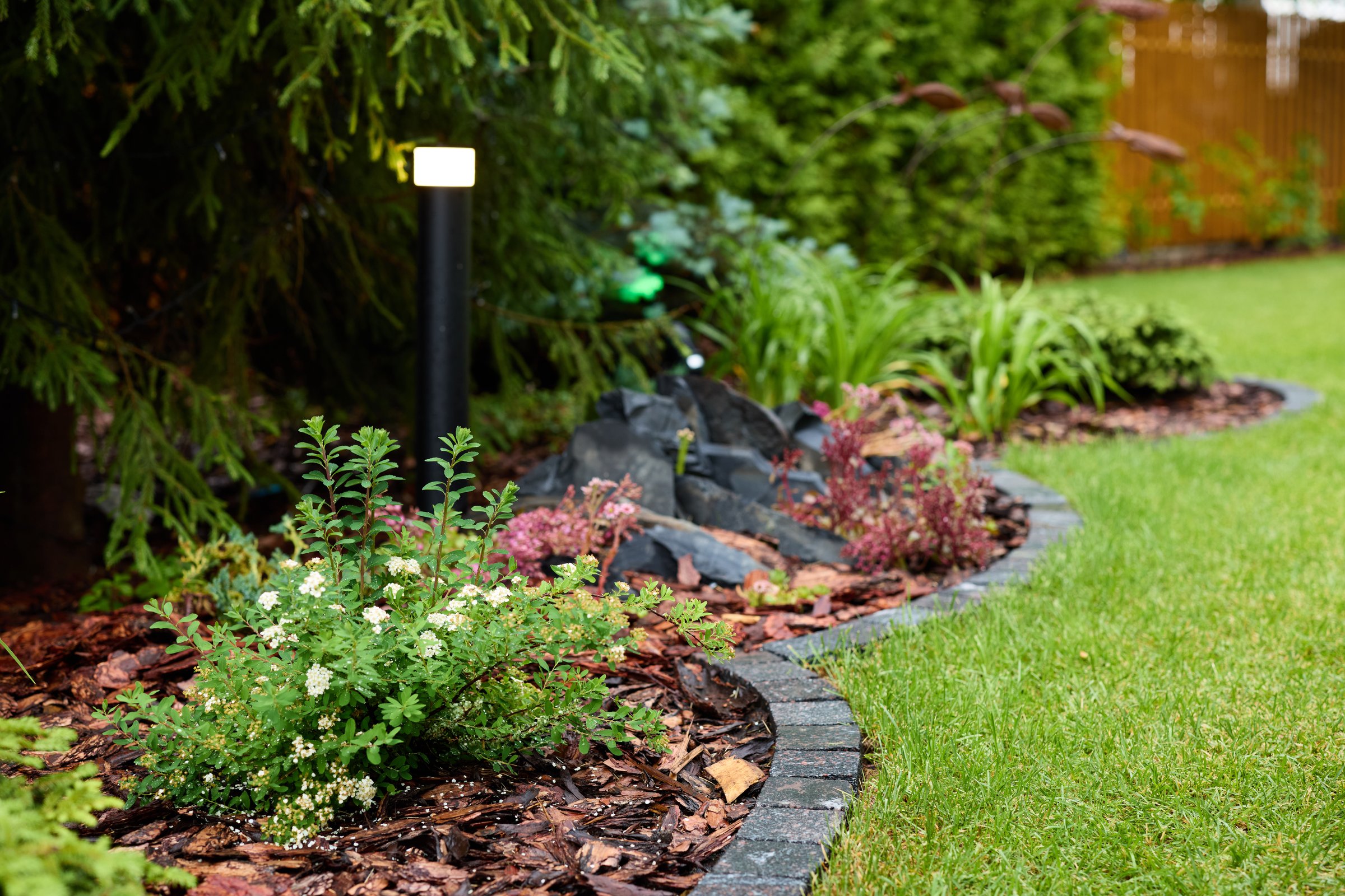 A beautifully picturesque garden filled with an array of vibrant plants and decorative rocks within a lush landscape