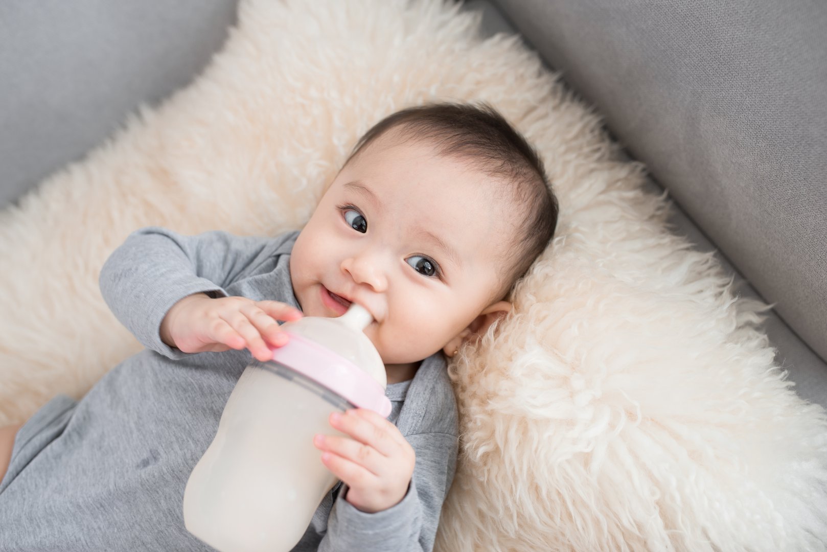 Asian baby infant eating milk from bottle, 9 months after birth