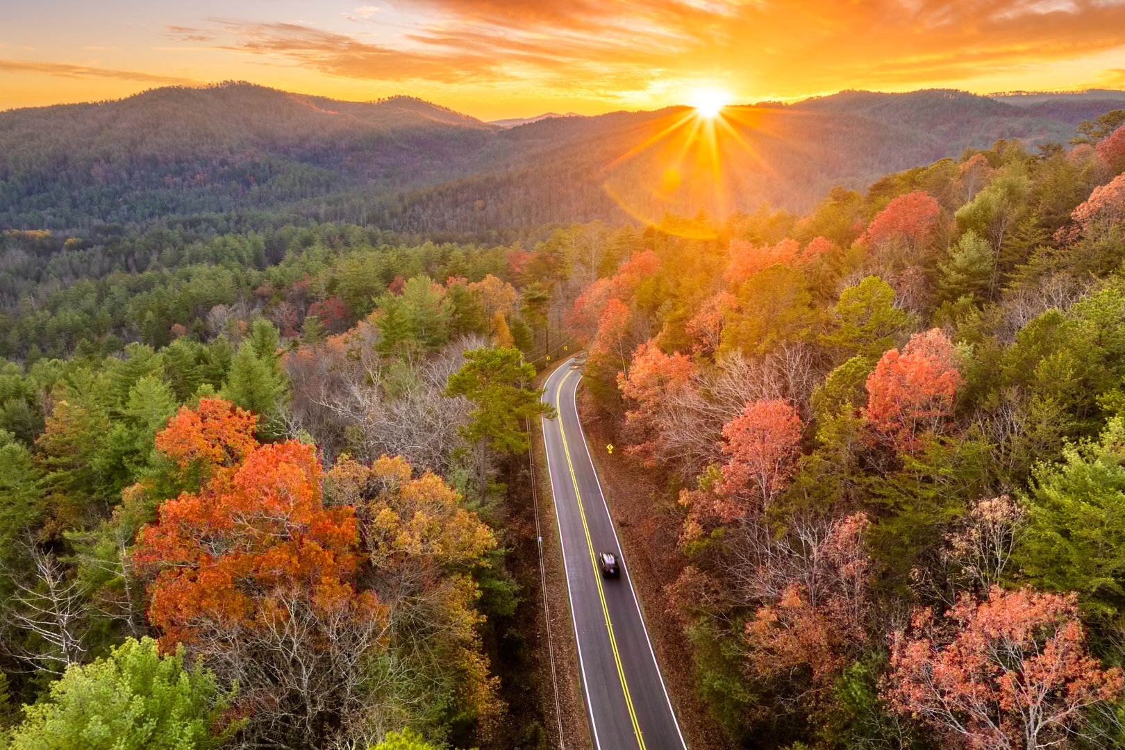 Peaceful mountain road in North Carolina during peak fall season at sunset. Appalachian landscape filled with vivid autumn colors.