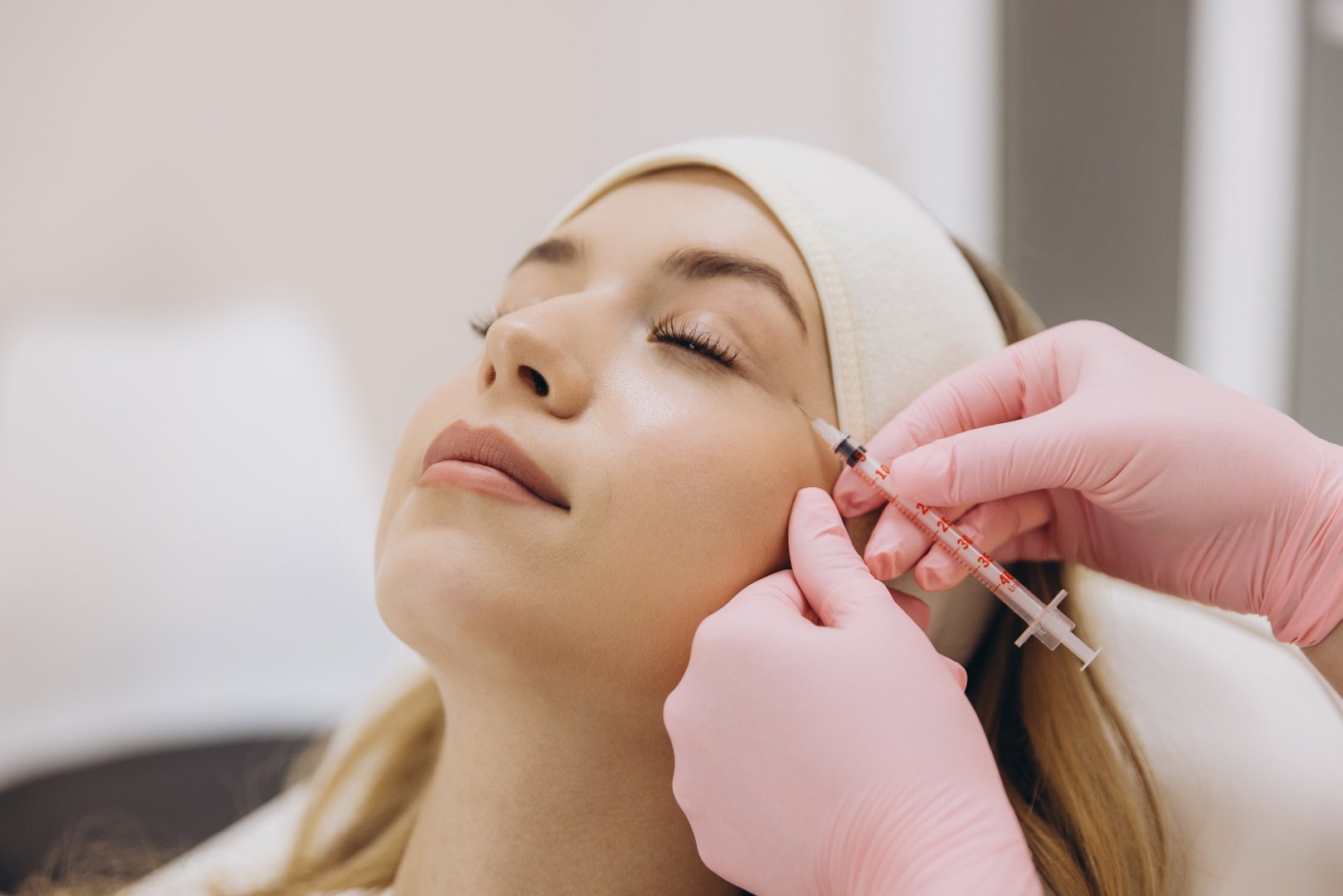 Skilled cosmetologist performing anti aging injection, treating patient's facial wrinkles during professional cosmetic procedure in clinic