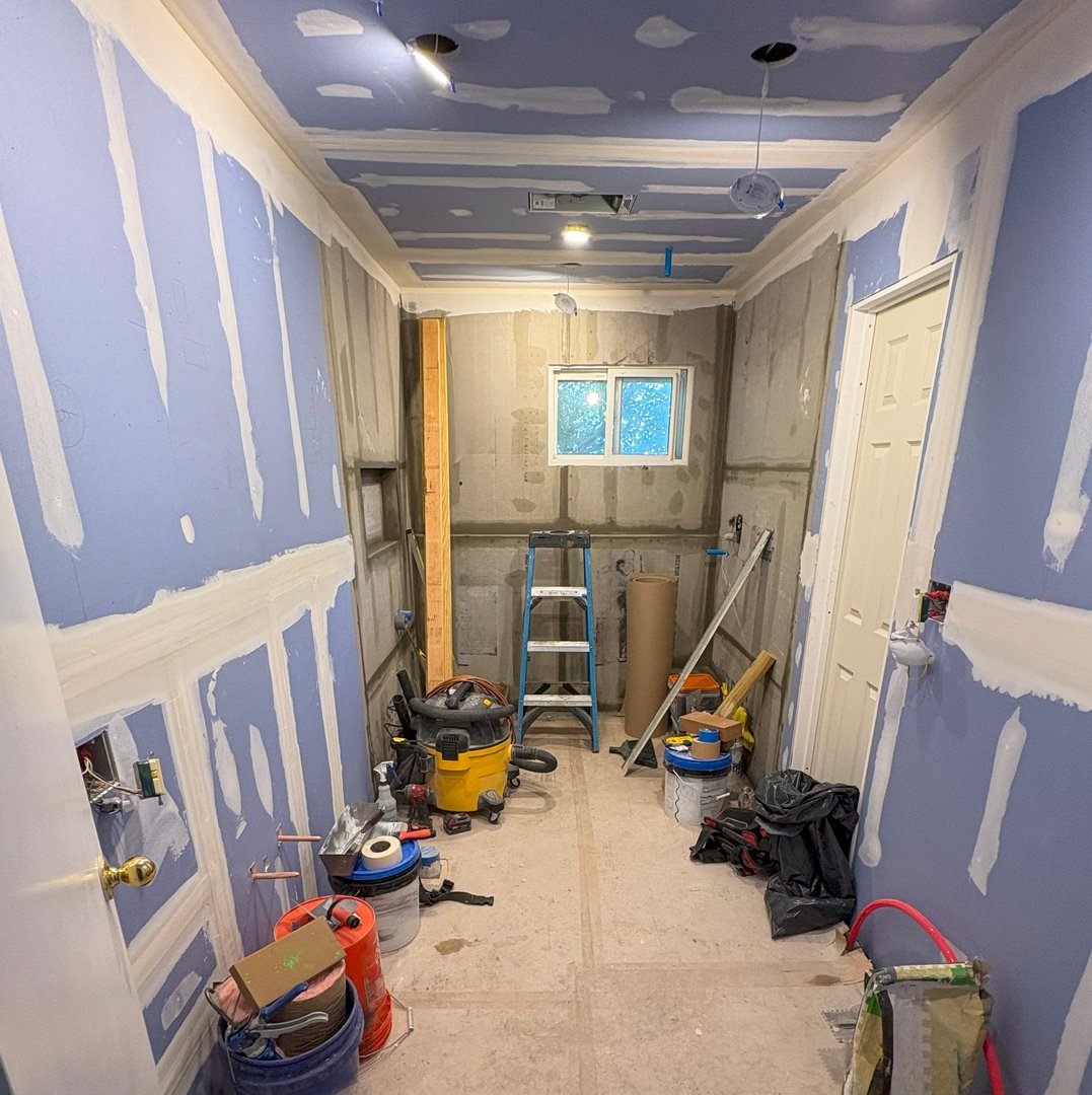 Walls in a residential area are being prepared, with tools and materials around.