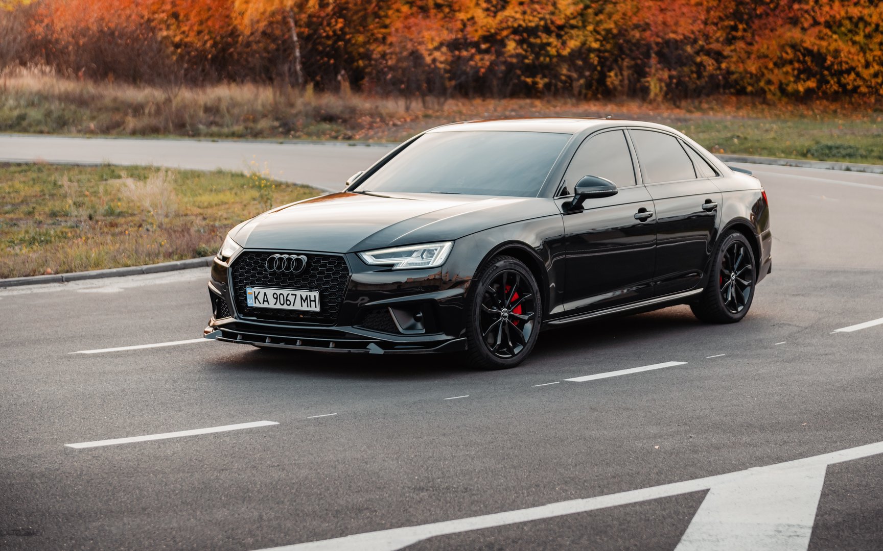 black Audi A4 on a road in autumn forest.