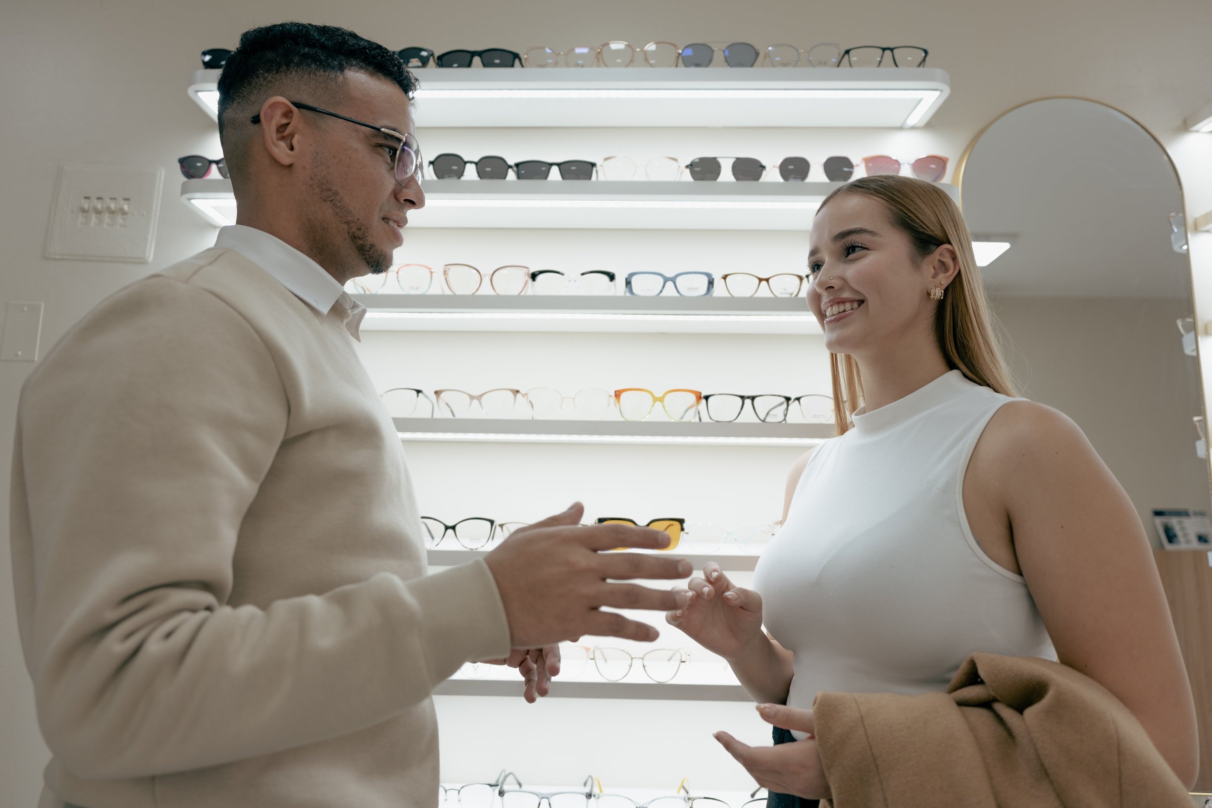 Young woman talking with a friendly optician at a modern optical boutique