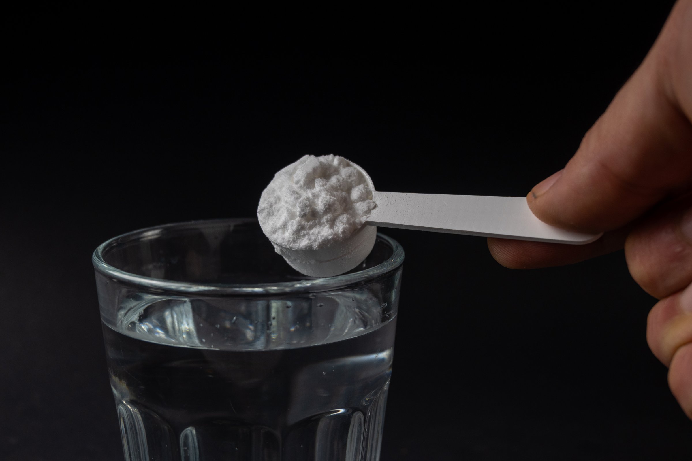Creatine Powder Scooping Into Water Glass