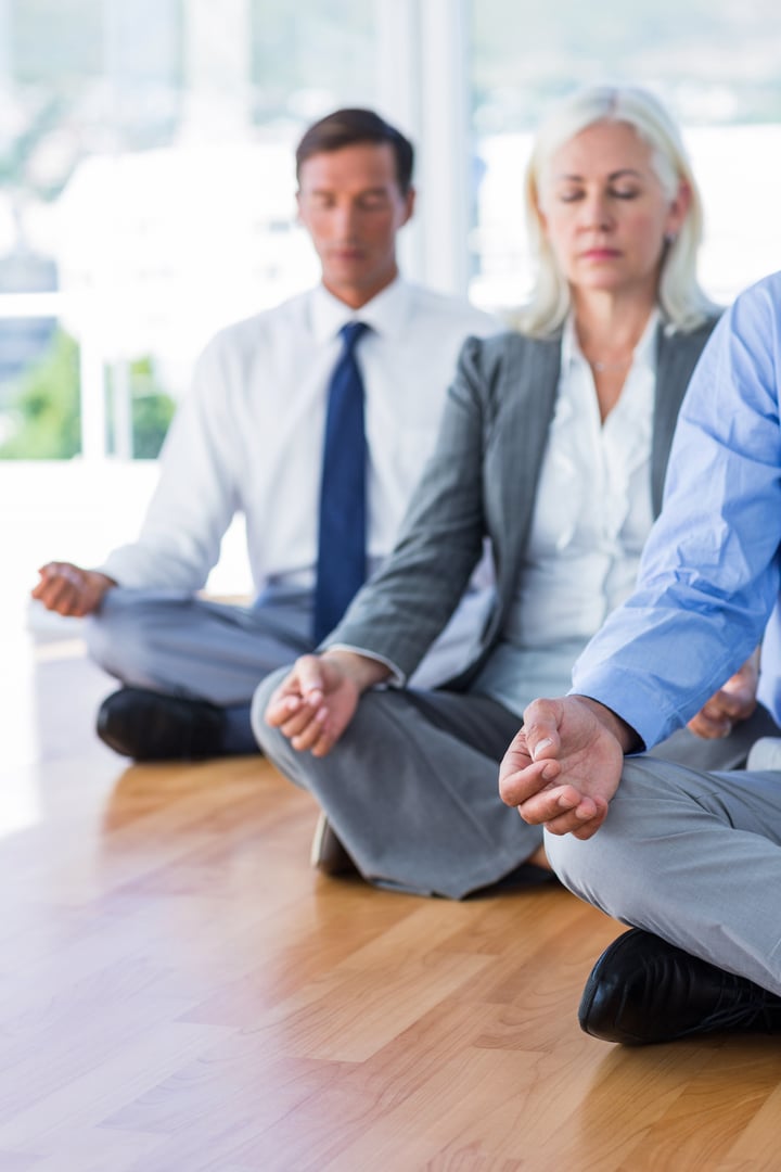 Business people doing yoga on floor in office