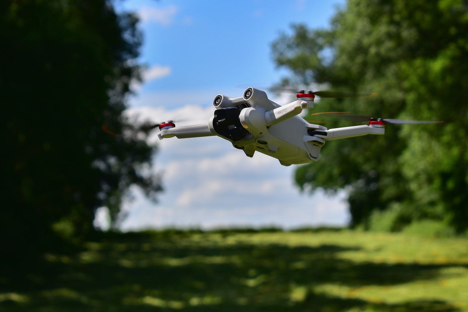 DJI Mini 3 Pro drone hovering in nature on a sunny day. State of the art technology for aerial footage and photography