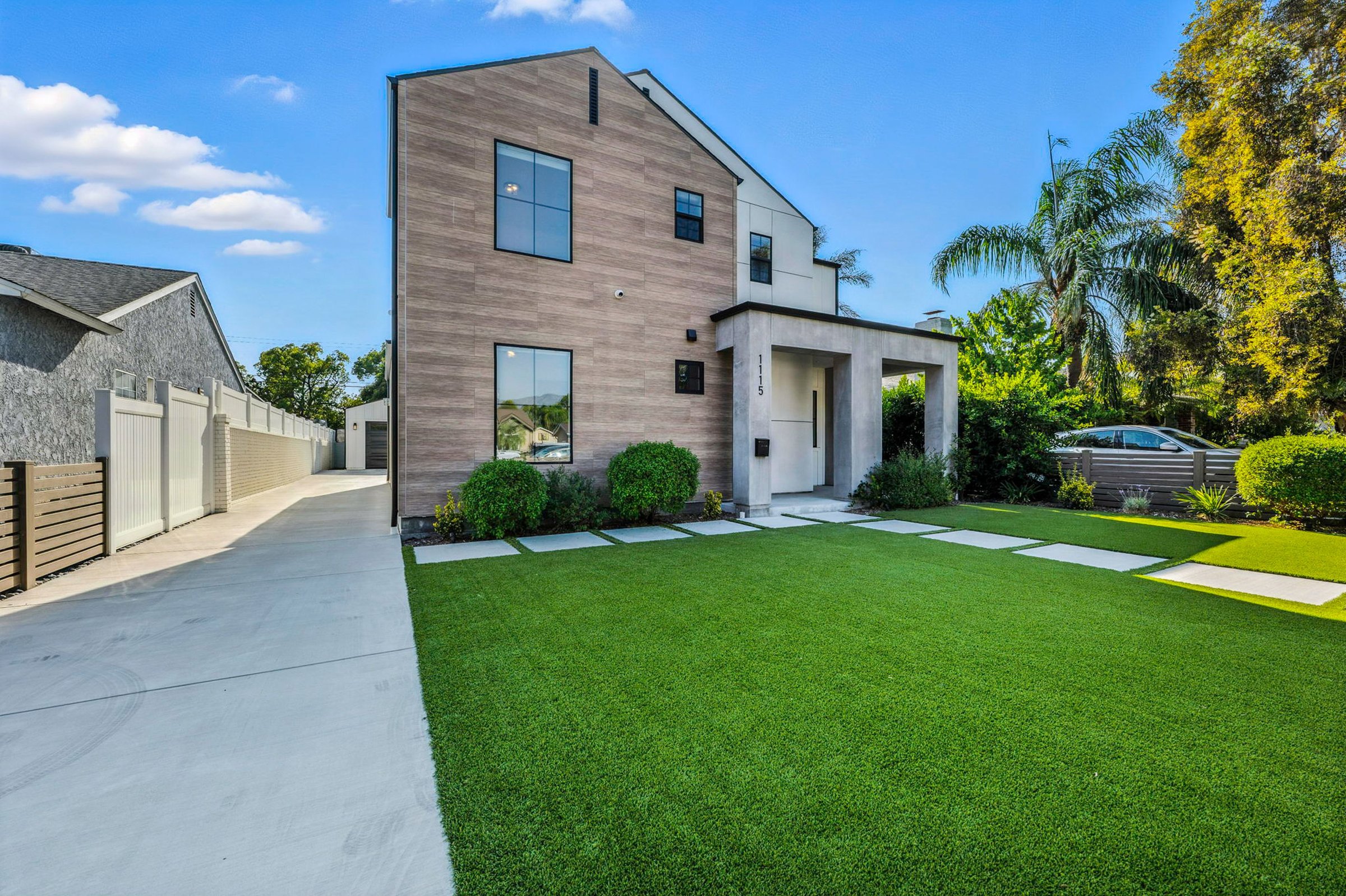 Modern suburban house with a well-manicured lawn and clear blue sky, showcasing contemporary architecture.