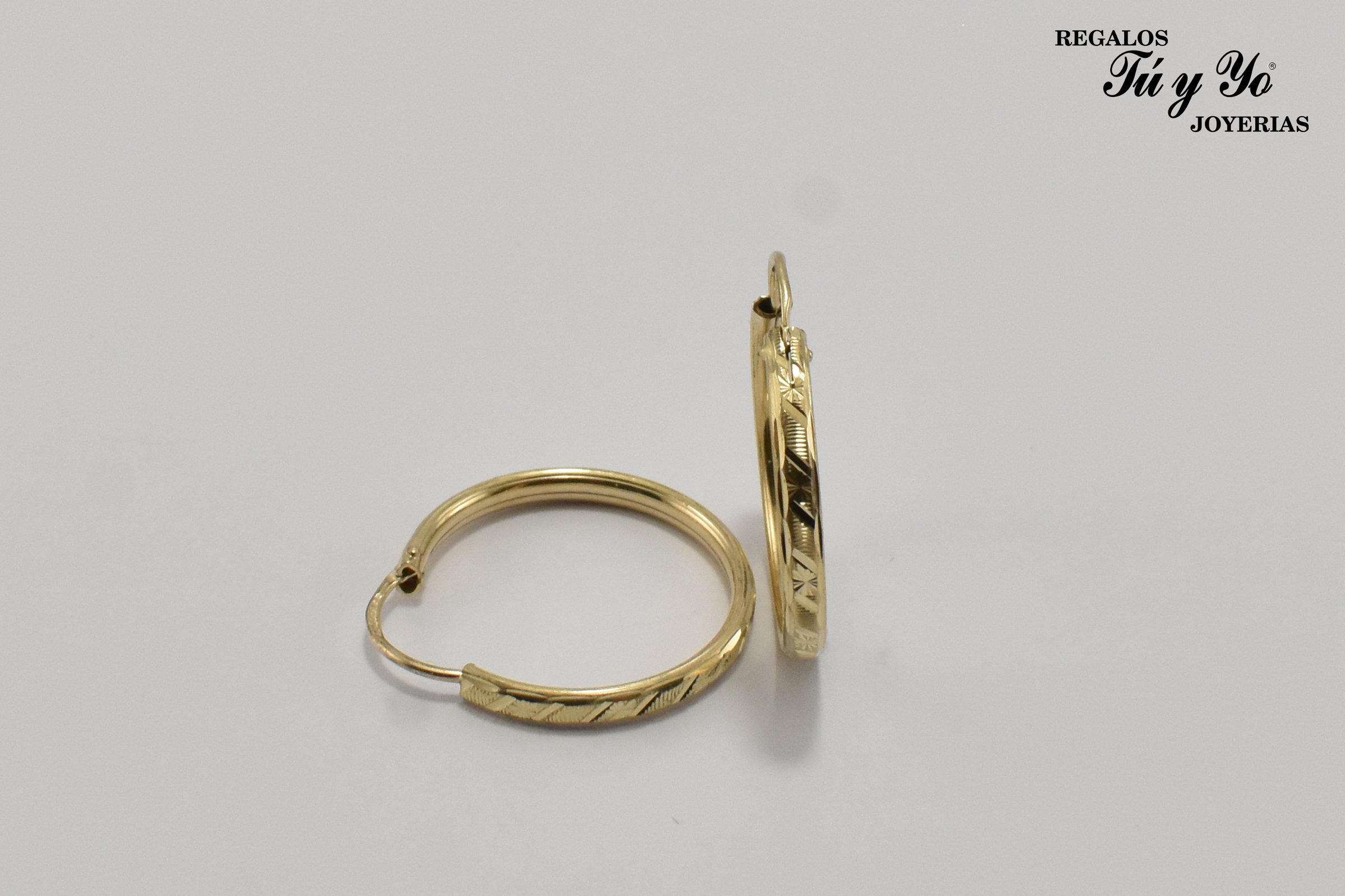 Gold hoop earrings with engraved details, displayed against a neutral background. Text "Regalos Tú y Yo Joyerías" in corner.