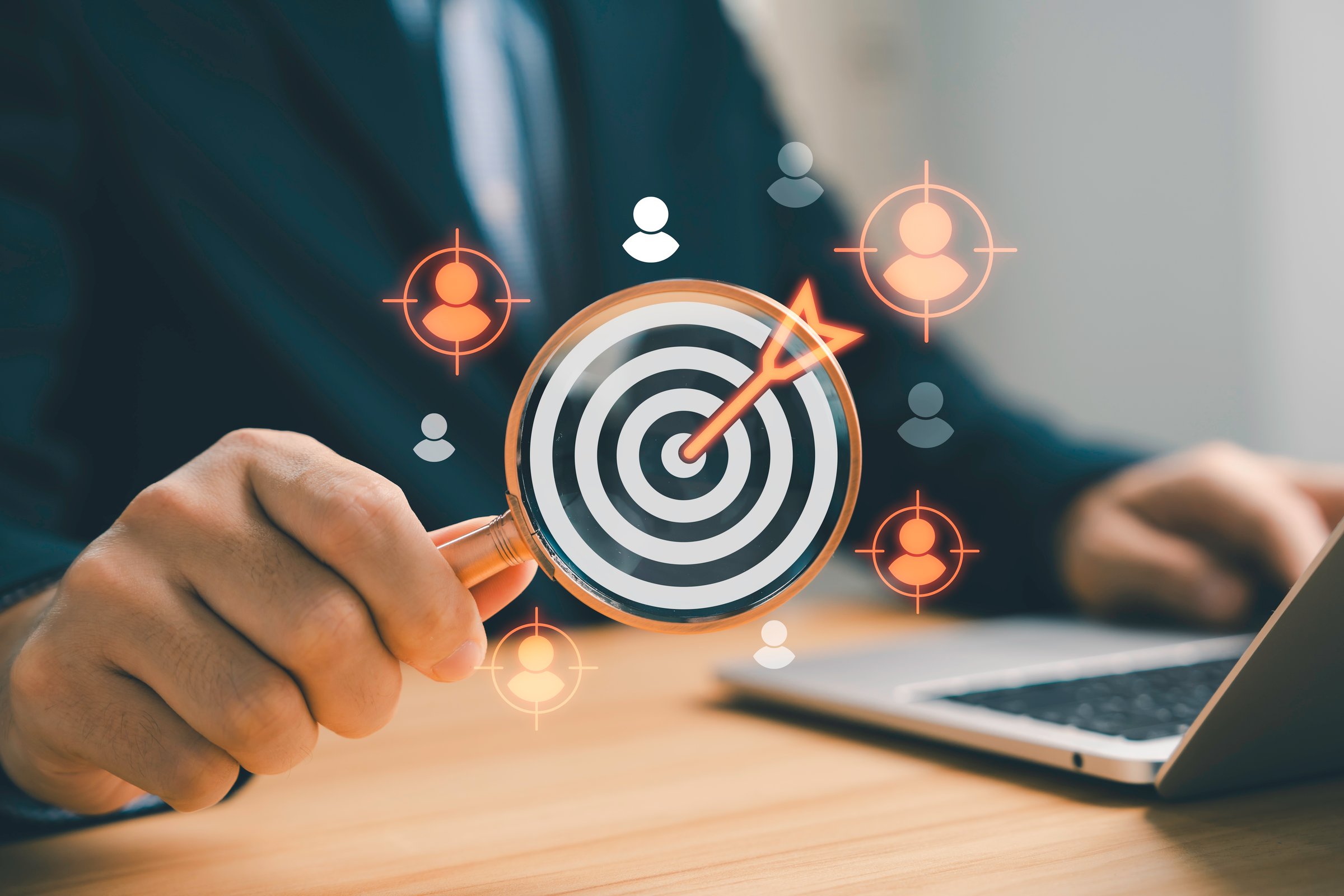 Businessman holding magnifying glass focusing on target with customer icons, digital marketing concept for audience targeting, business strategy, customer analysis, and market research.