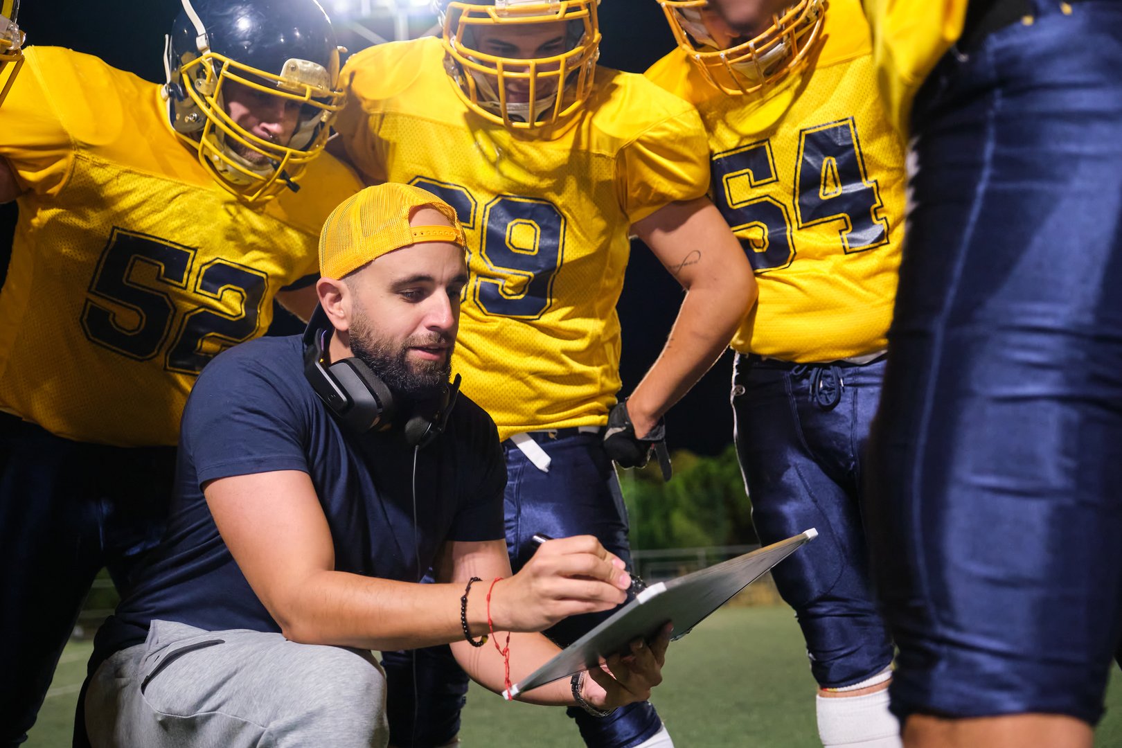 Coach explaining game tactics to football players on the field