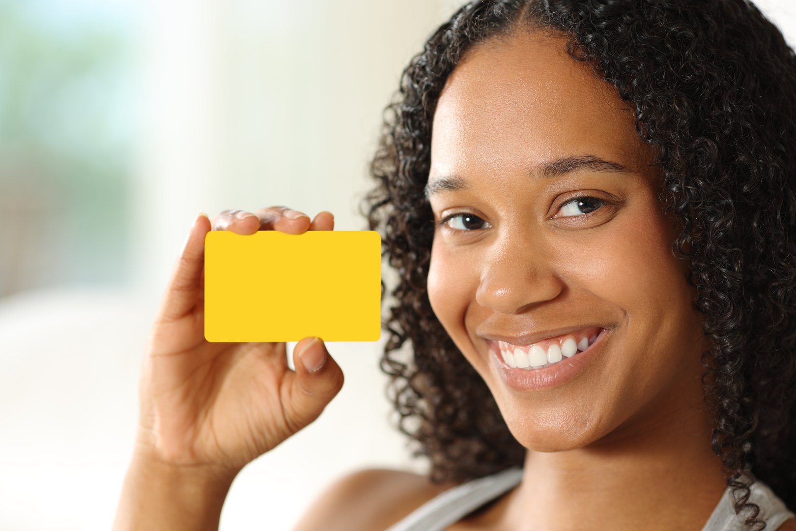Happy black woman showing blank card at home