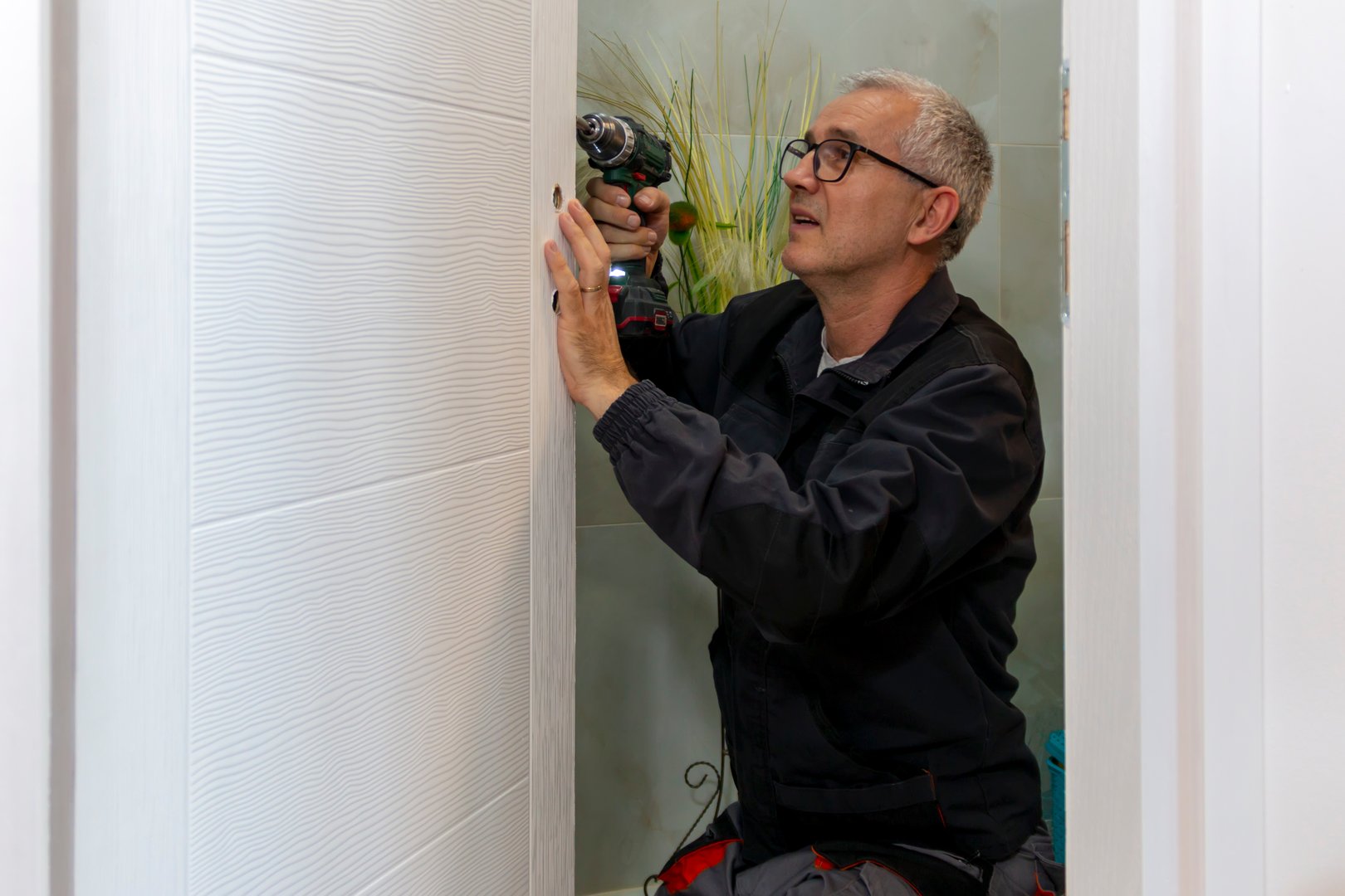 Installation of a lock on the wooden door. Screwdriver is used by carpenter to install lock handles in room door