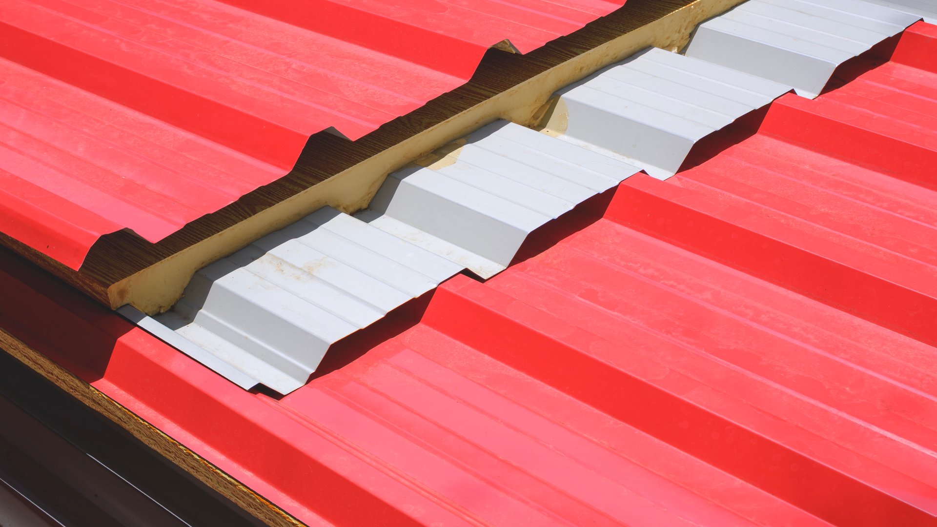 Red corrugated metal sheet roof with PU foam insulation stacked on the ground for install house roofing work in home construction site