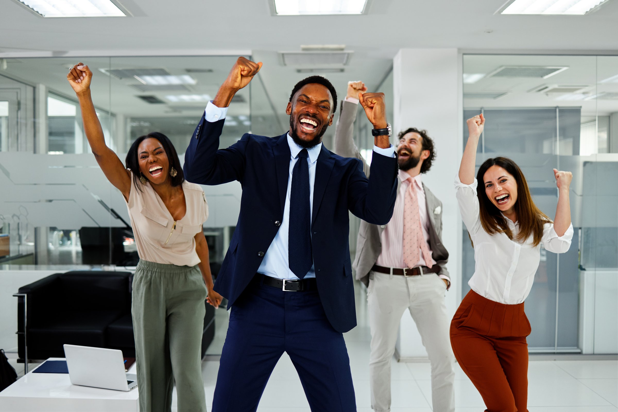 Diverse business team celebrating victory with joy and excitement in the office