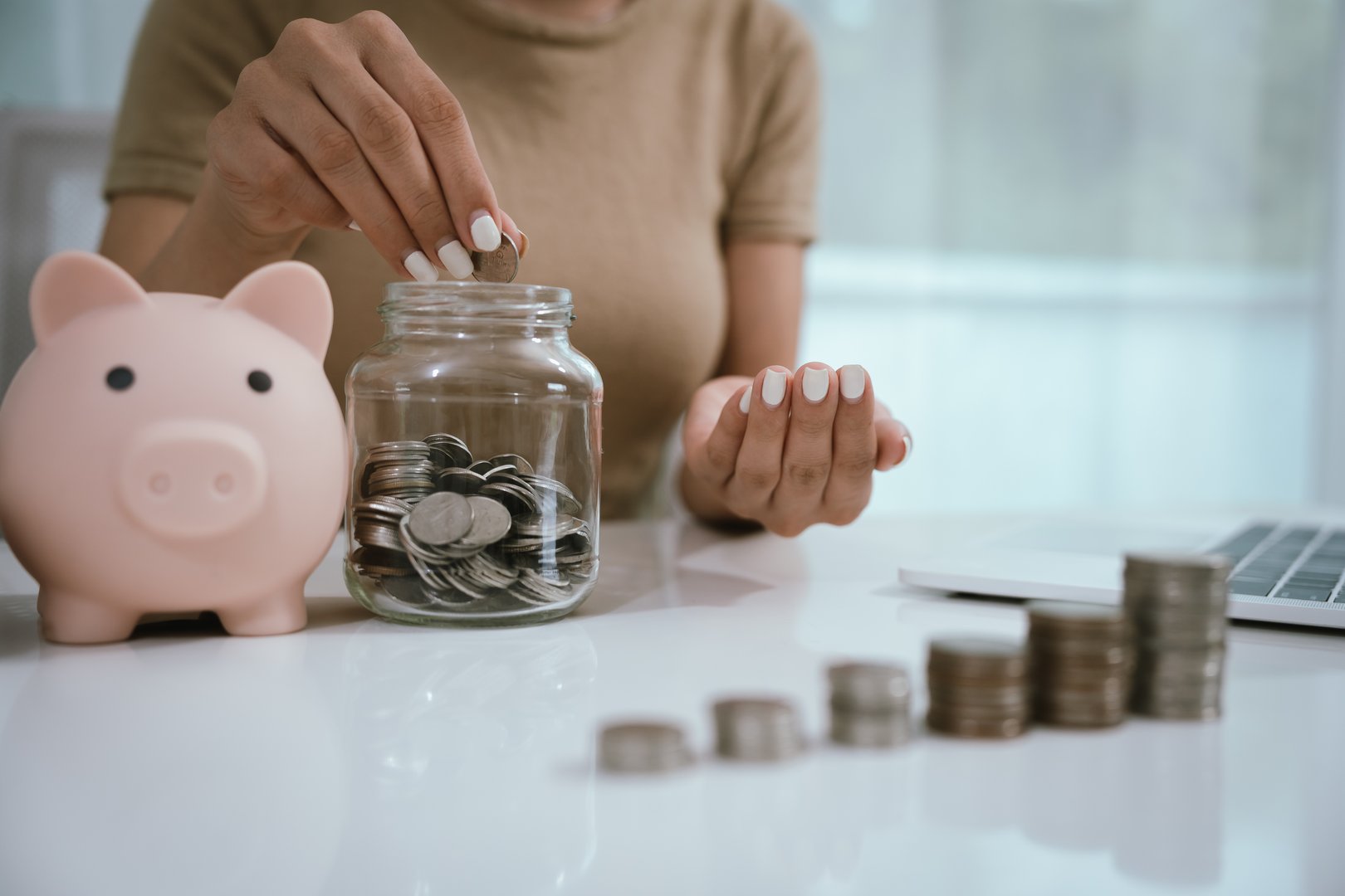 An Asian woman plans to divide her money into coins and a piggy bank, symbolizing budgeting, financial planning, saving, and smart money management.