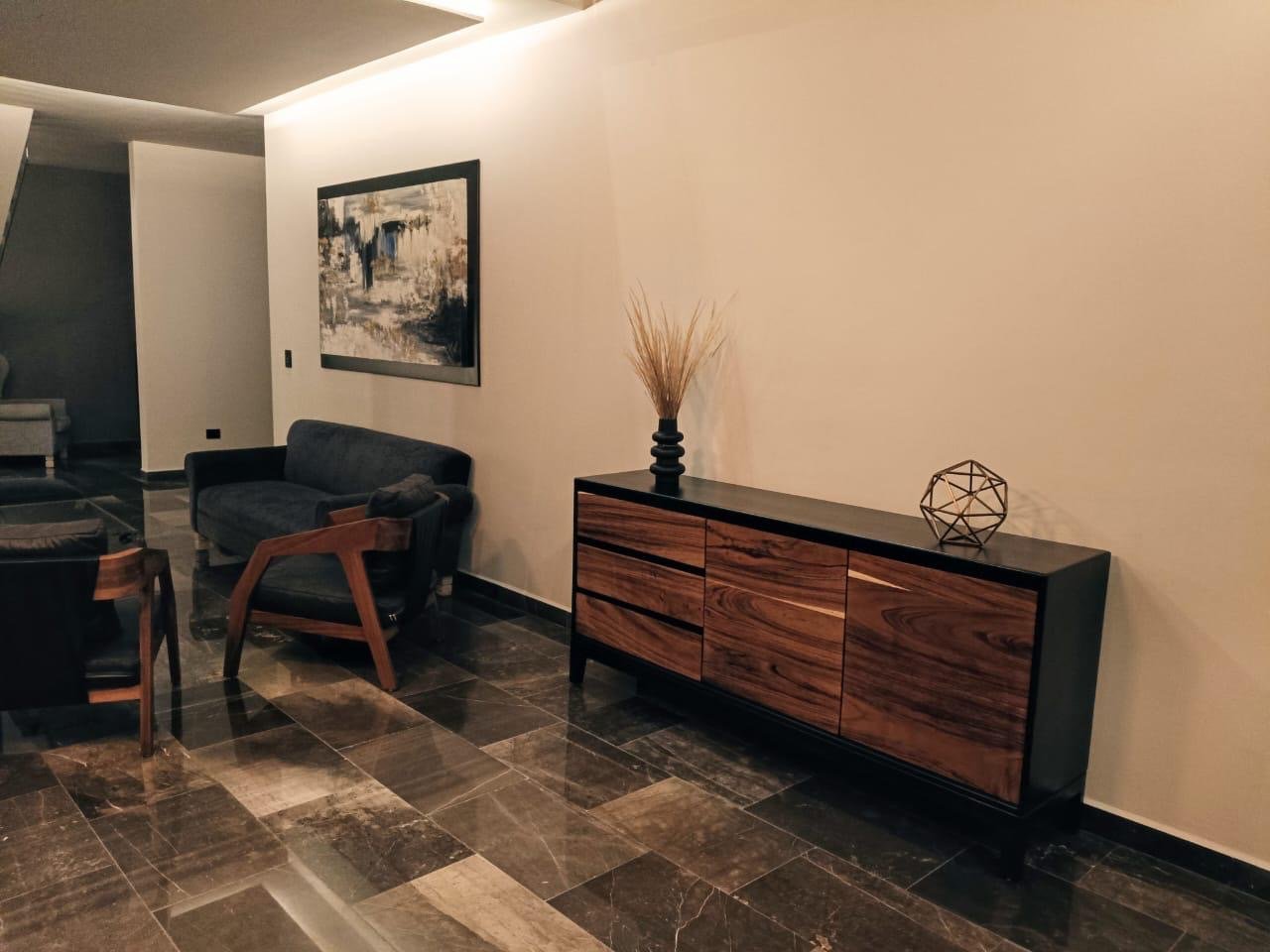 Consola moderna de madera de parota con cuerpo lacado en negro mate, dos puertas laterales y 3 cajones centrales con jaladeras ocultas