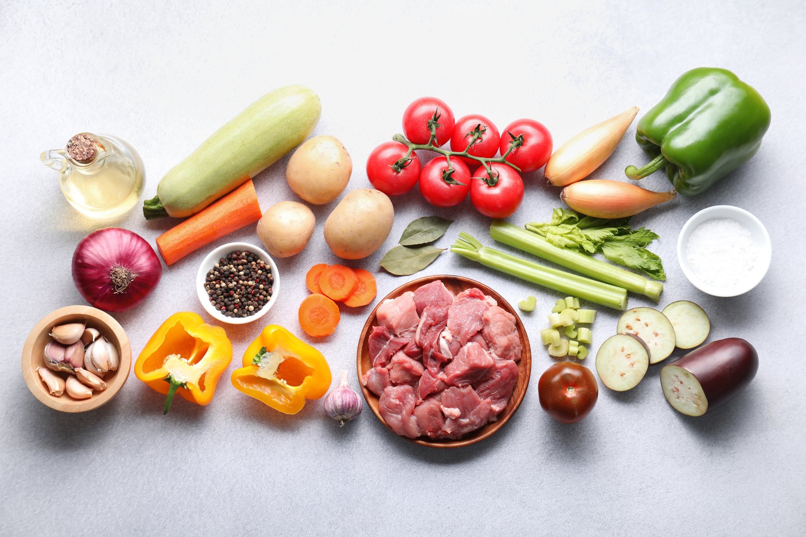 Cooking stew. Uncooked meat and vegetables on light grey table, flat lay