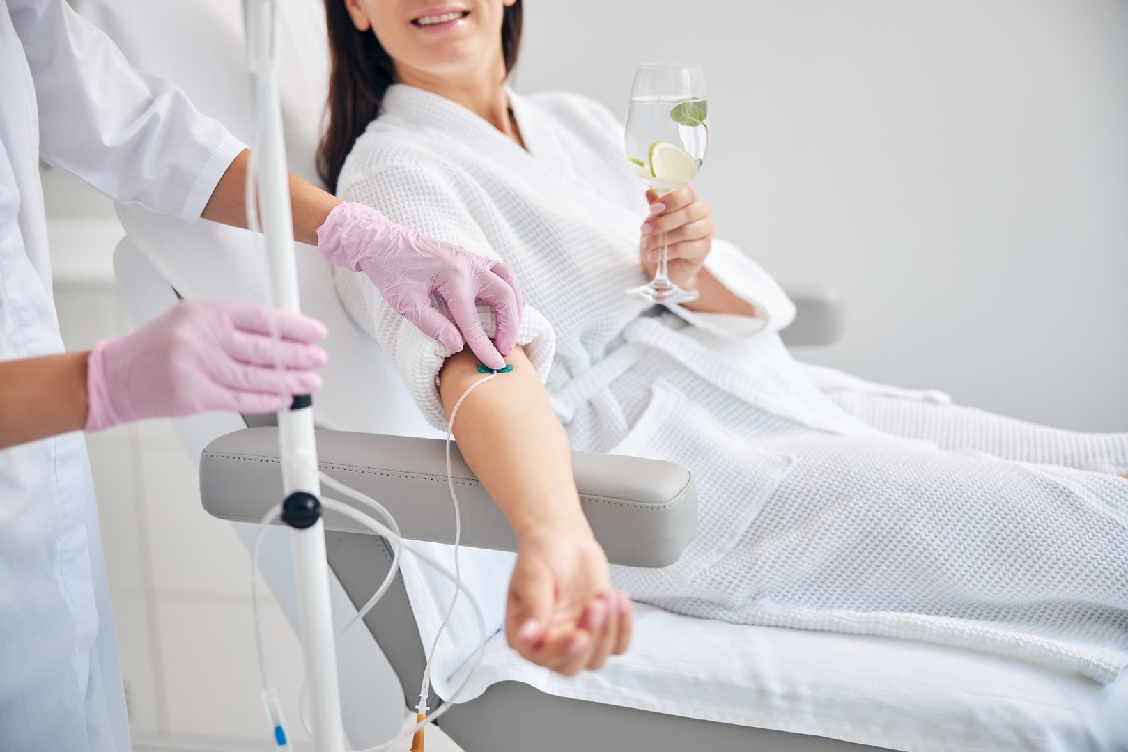 Cropped photo of a woman with a glass of drink sitting in a cosmetic chair