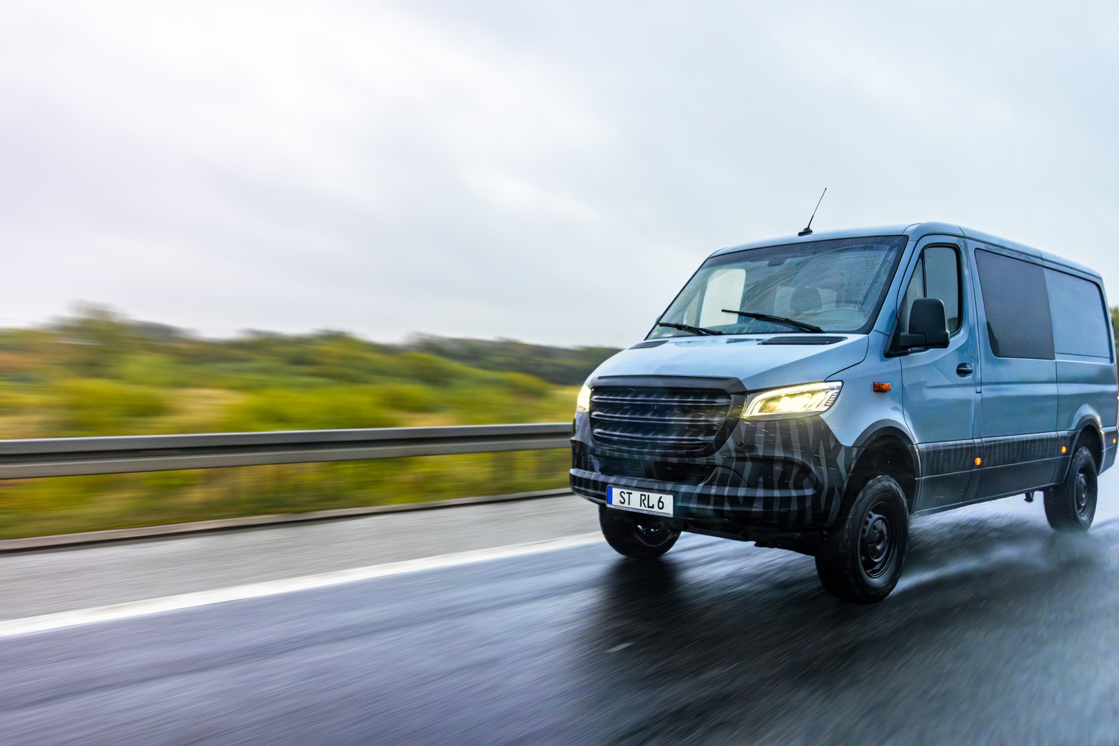 Modern gray van driving fast on a rainy highway, symbolizing movement, freedom, and professional logistics. The shot captures energy and motion in wet weather.