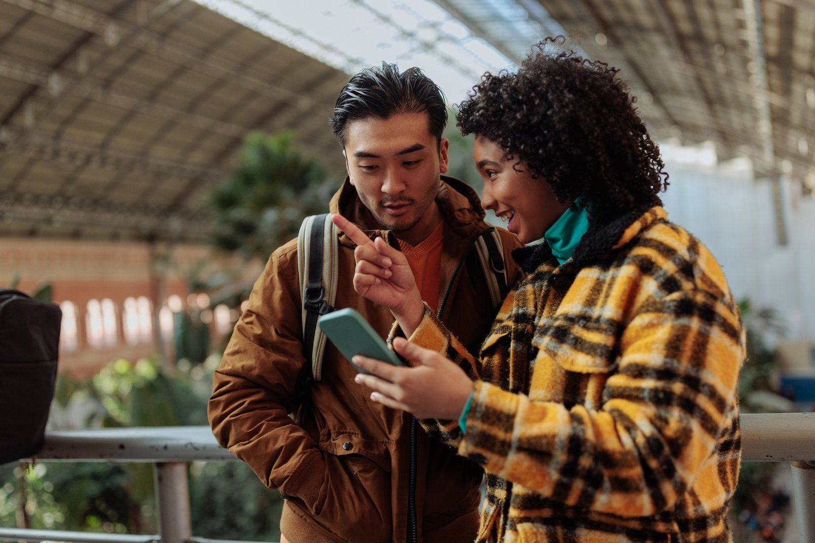 Young tourists using smart phone app for navigating inside train station in madrid, spain
