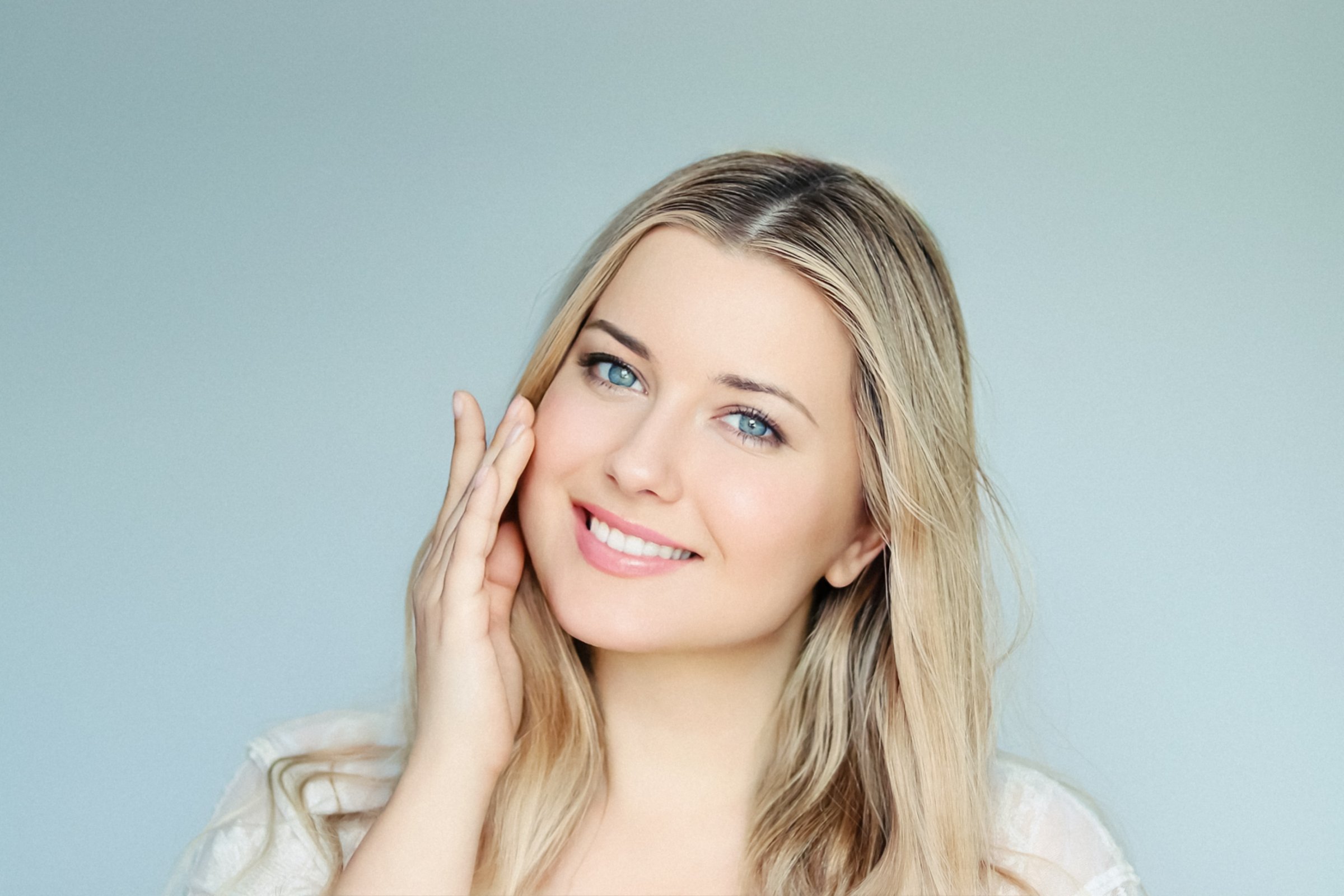 Natural beauty, skincare and cosmetics, smiling blonde woman with blue eyes and radiant face applying moisturiser, light mint background