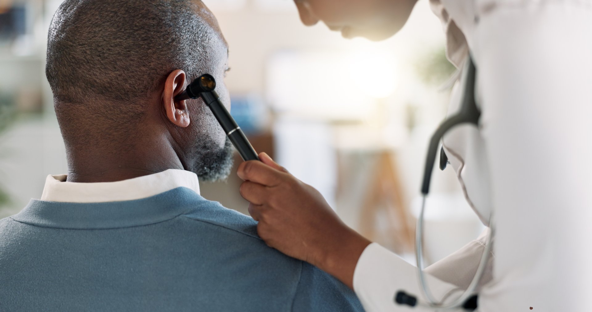Doctor, check and ear with man, patient and test for tinnitus or hearing problem in clinic. Hospital, otoscope and back with healthcare, wellness and physician consultation with otolaryngology exam