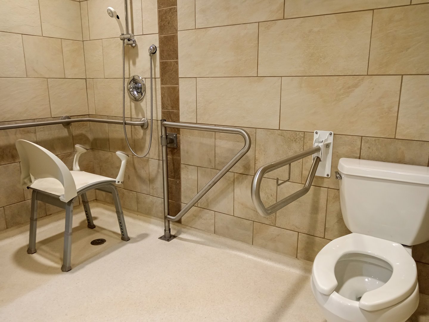 Medical shower chair with grab bars for seniors and disability person in bathroom care home facility.