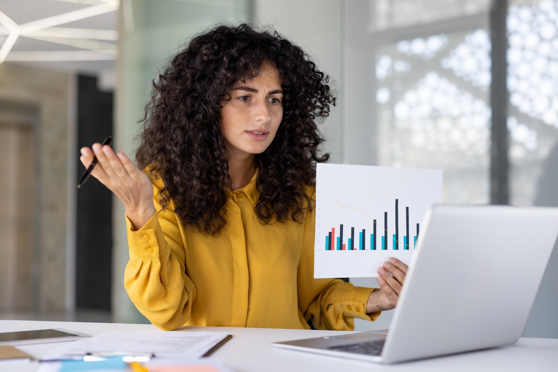 Businesswoman financier demonstrates and shows revenue graph at online conference meeting. Woman serious and focused at online presentation talking about company achievement results.