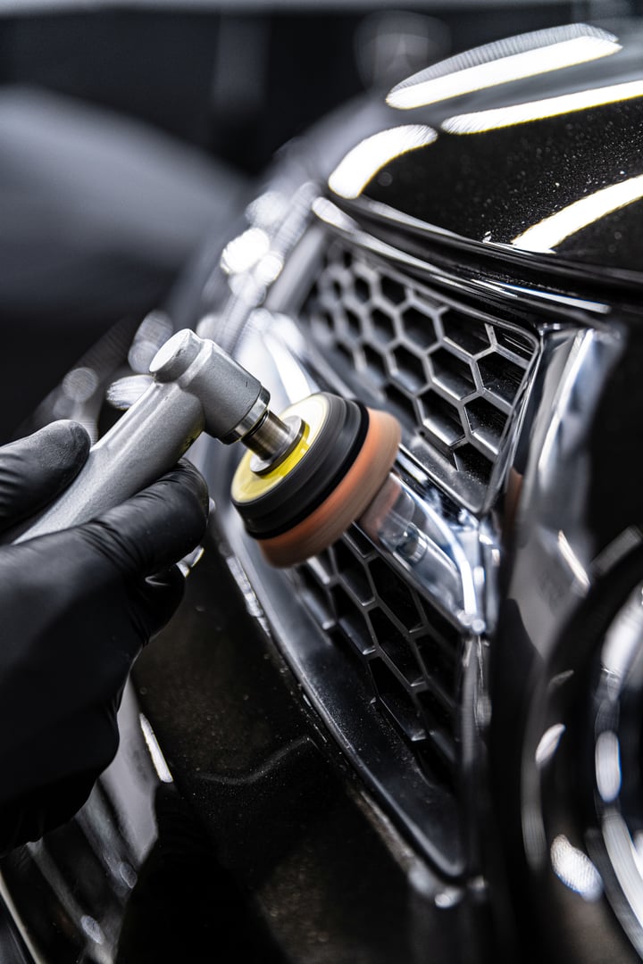 Car detailing technician polishing chrome shine decor on car with eletric polisher