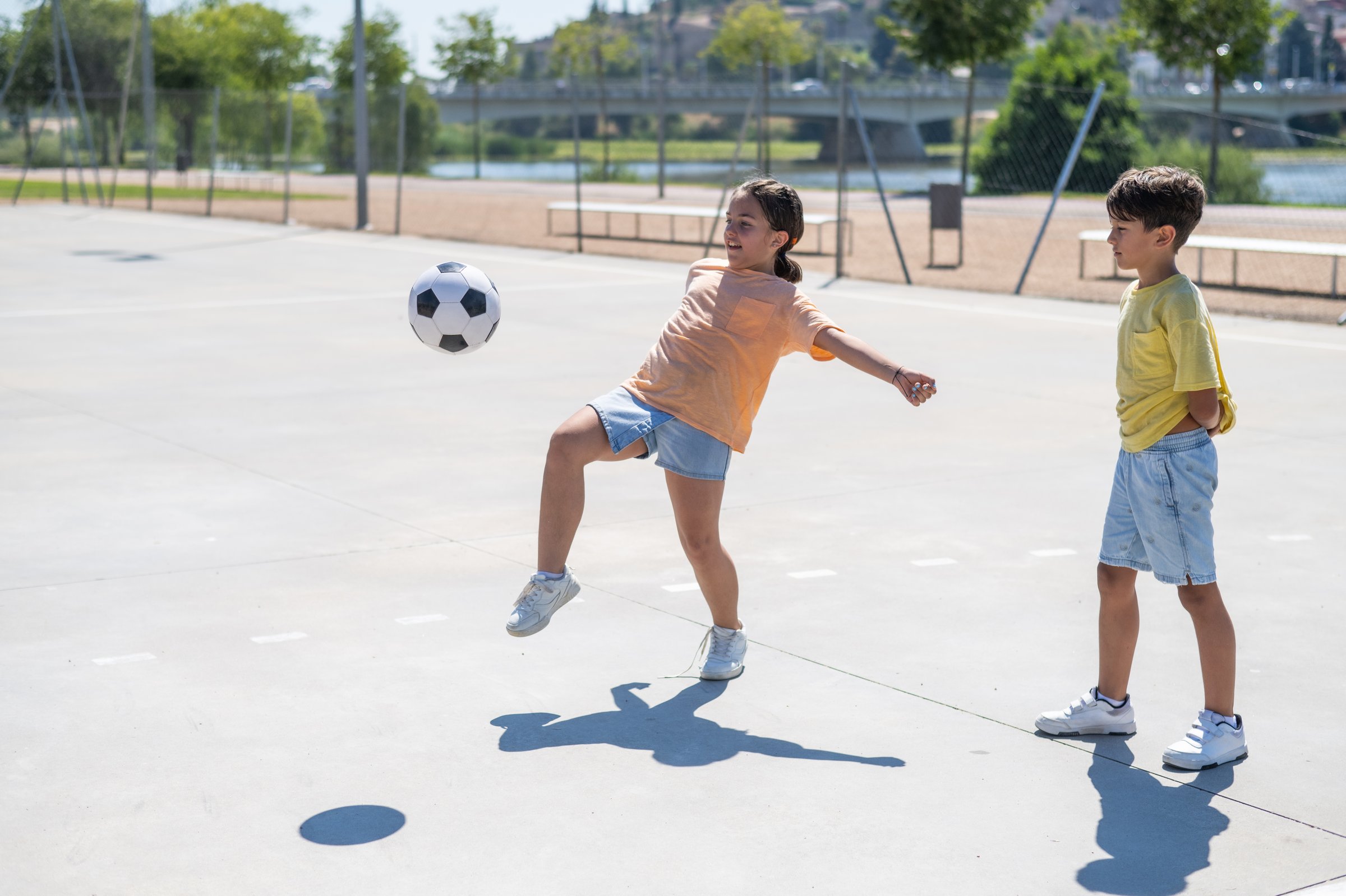 Little Primary-Aged Children Playing Ball In The Schoolyard