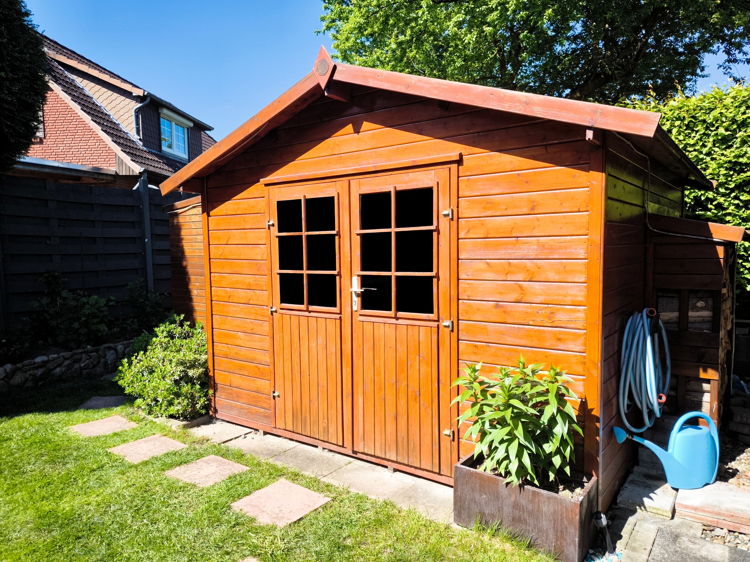 Side view of wooden garden shed glased in teak color